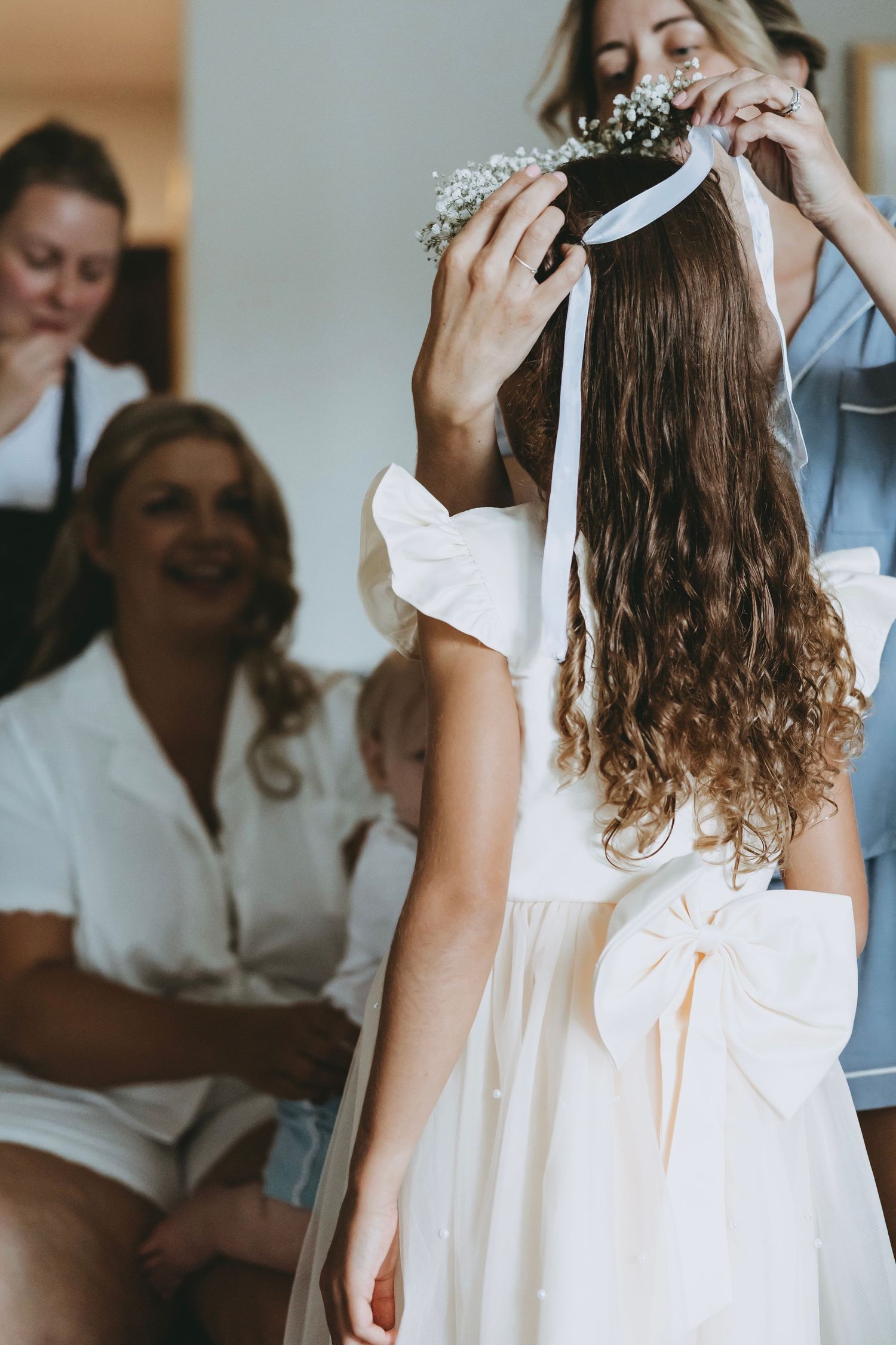Young girl in a white dress twirls during a wedding preparation moment.