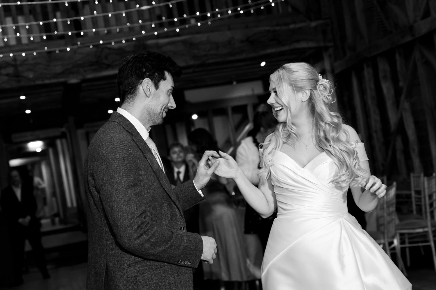 Couples dancing under string lights at an evening wedding reception.