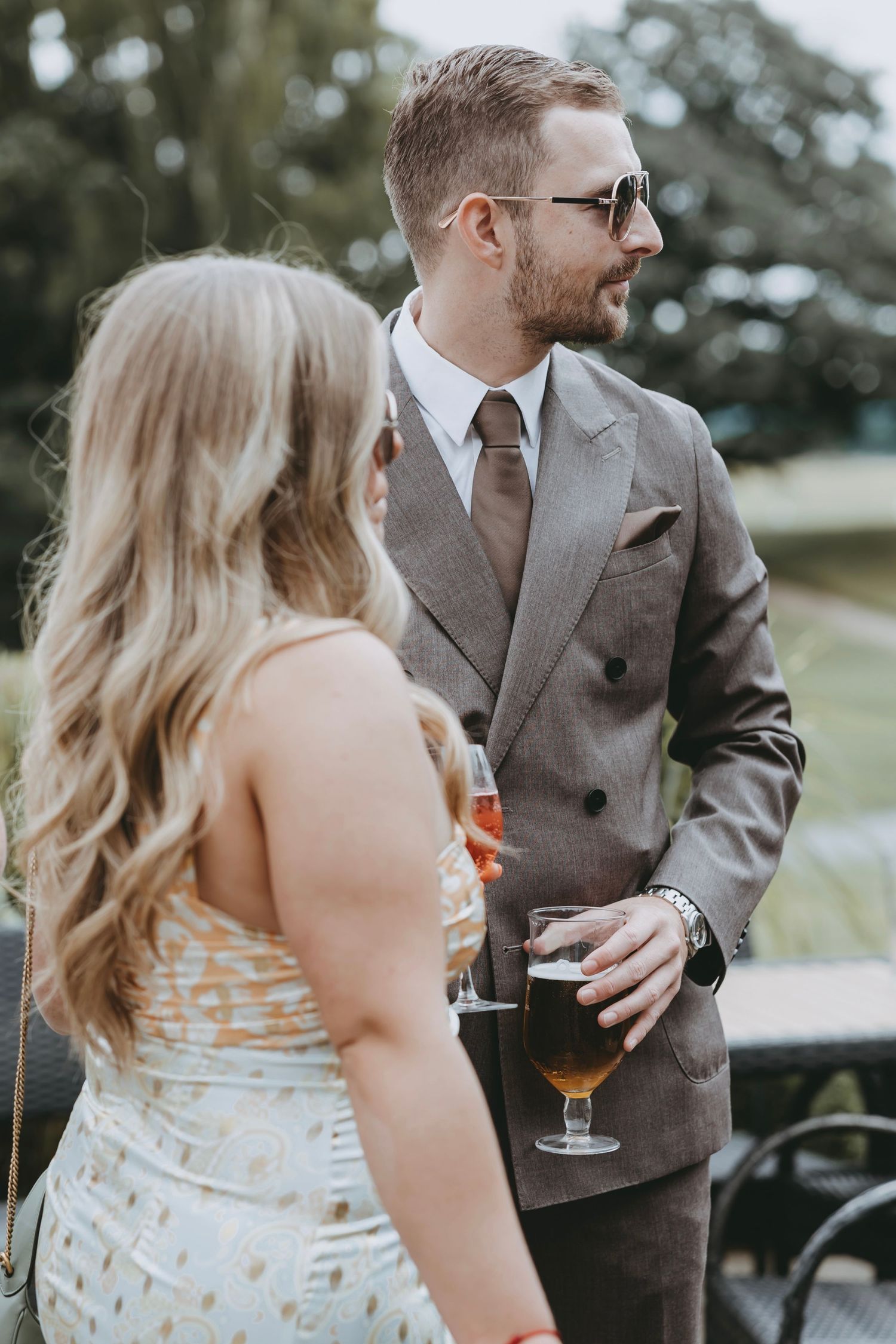 Wedding guests in formal attire socialize during an outdoor reception.
