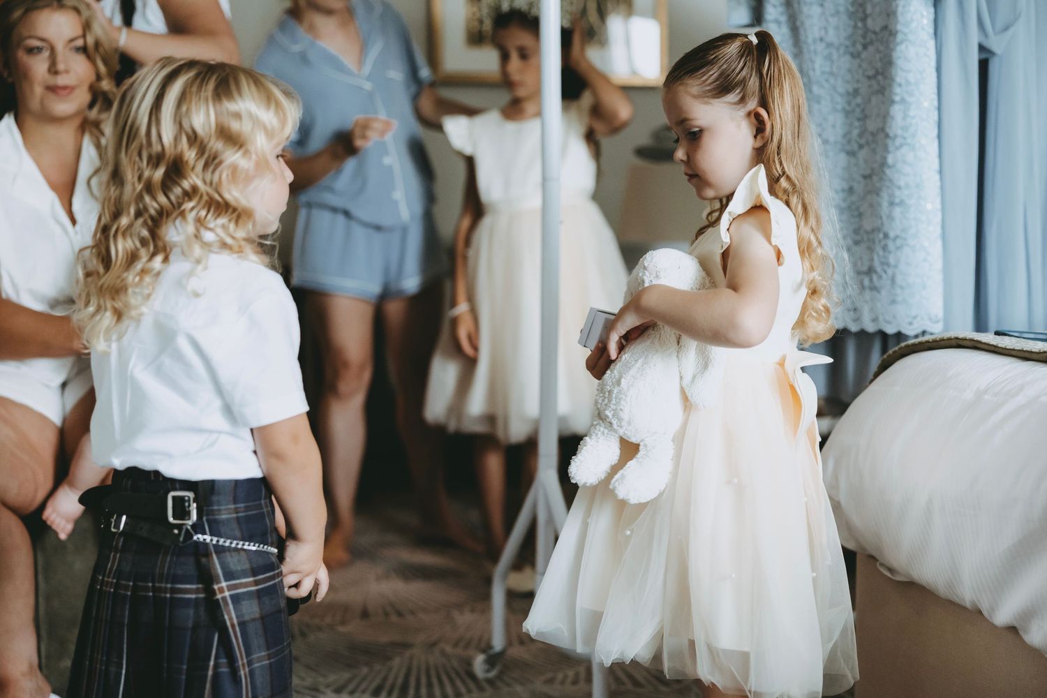 Wedding preparation scene with attendants in white and formal attire.