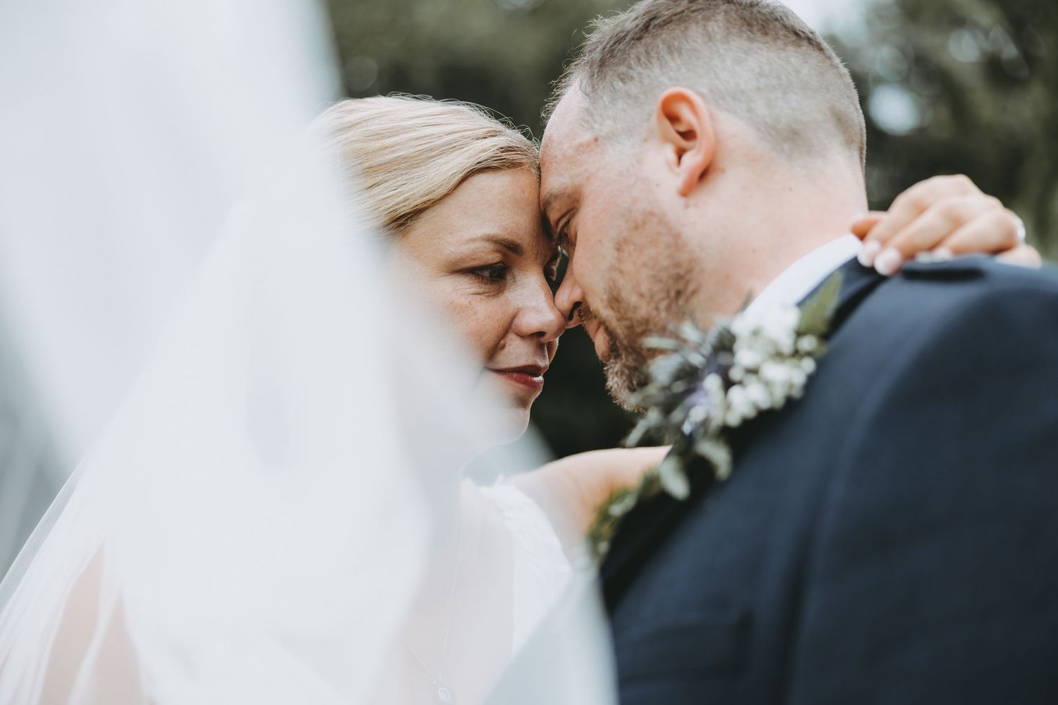 Intimate black and white wedding portrait showing tender moment between newlyweds.
