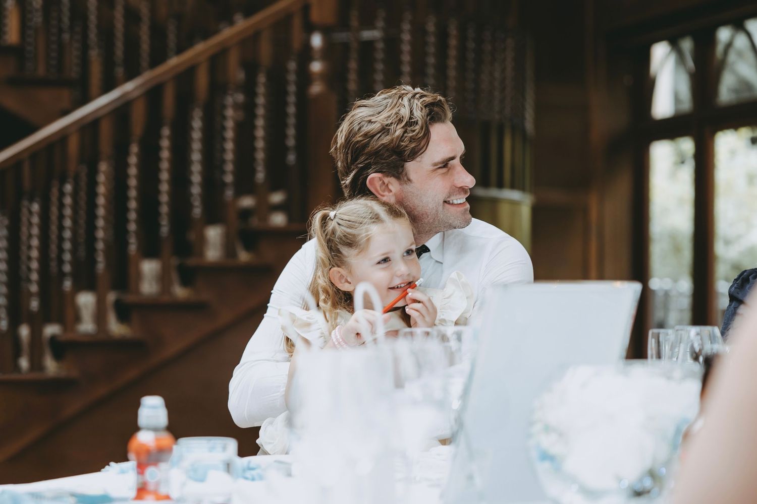 Reception guests enjoying conversation at decorated dining tables in wood-paneled room.