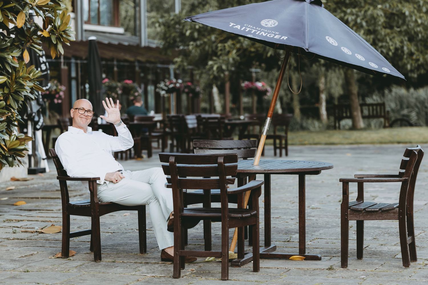 Empty wooden tables and chairs arranged outdoors for an event.