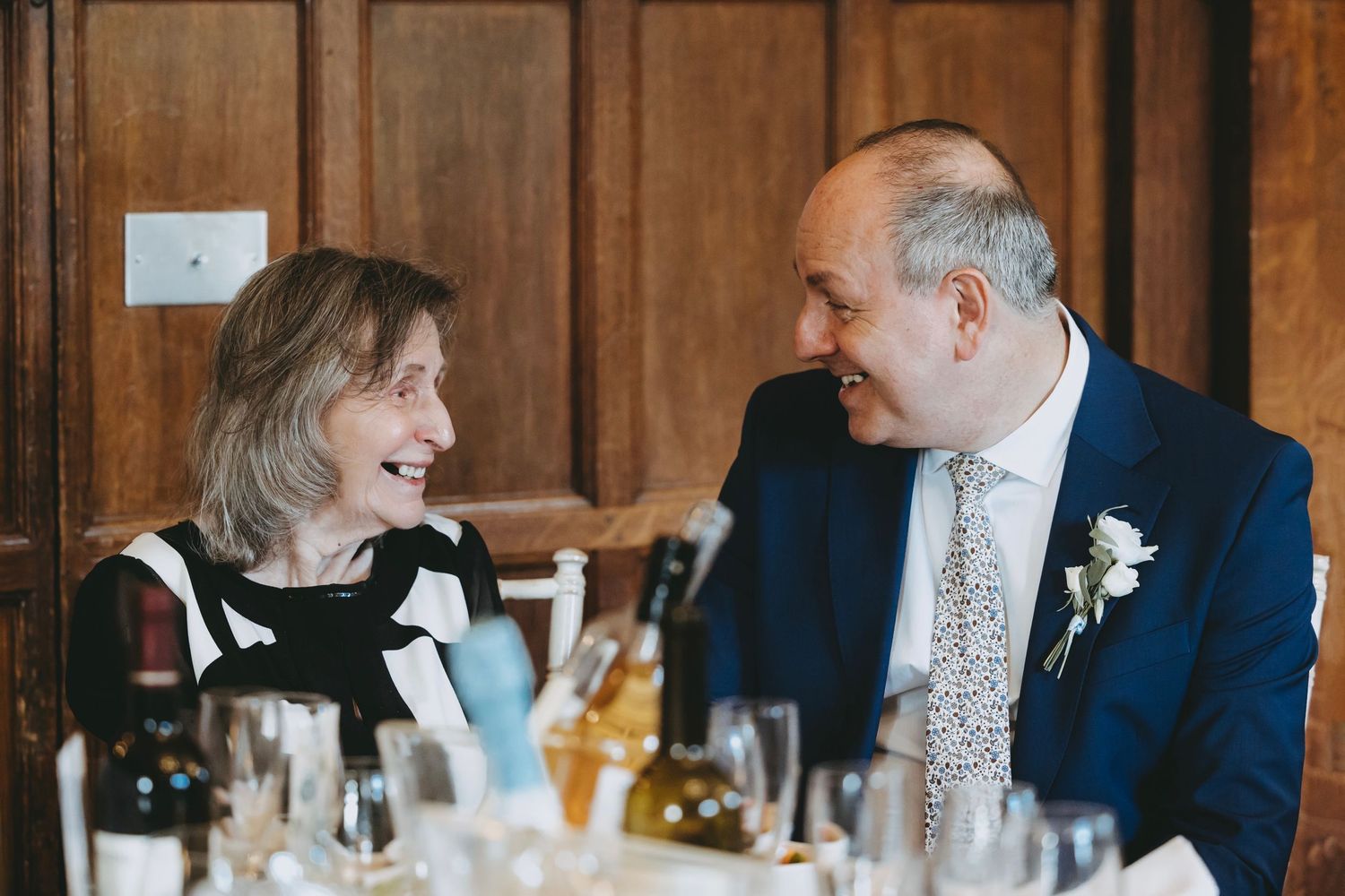 Guests sharing laughter at an elegant dining event with formal table settings.