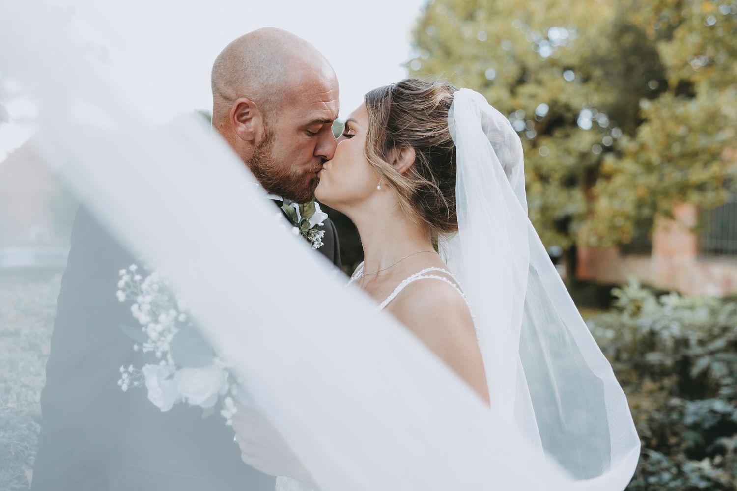 Ethereal wedding portraits with flowing veil in natural outdoor setting.