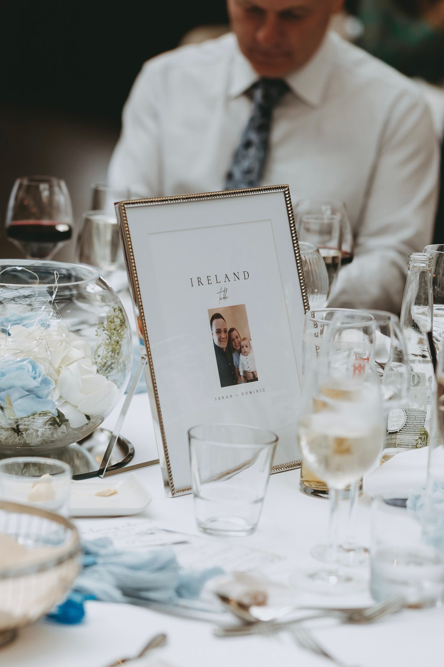 Wedding reception table decorated with place cards and formal table settings in soft natural light.