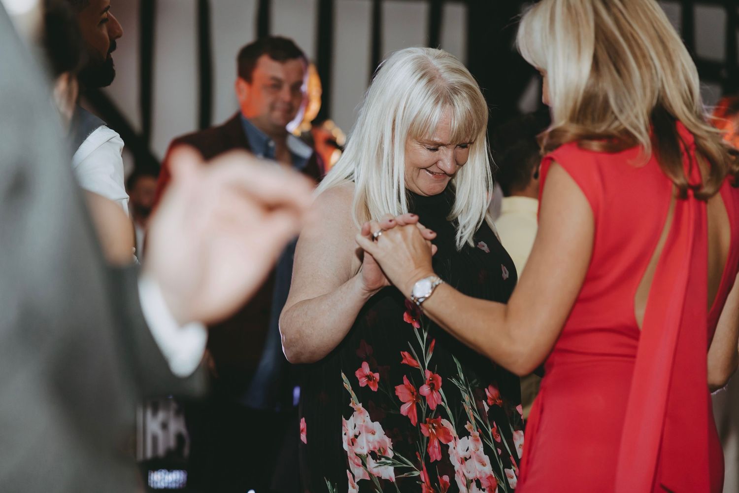 Wedding guests dancing and socializing during an evening reception with colorful lighting.