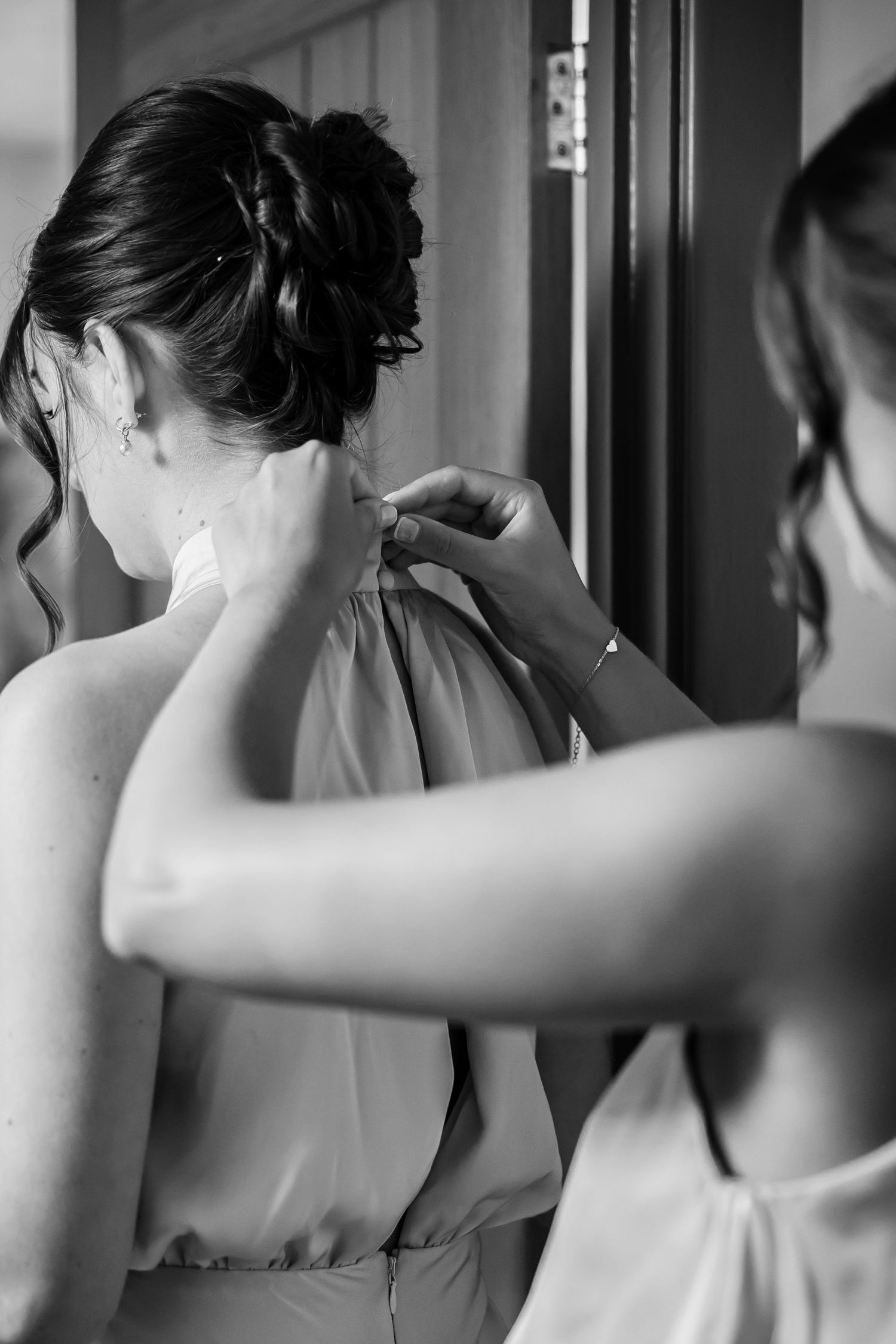 Black and white photo series showing wedding party members helping with hair styling.
