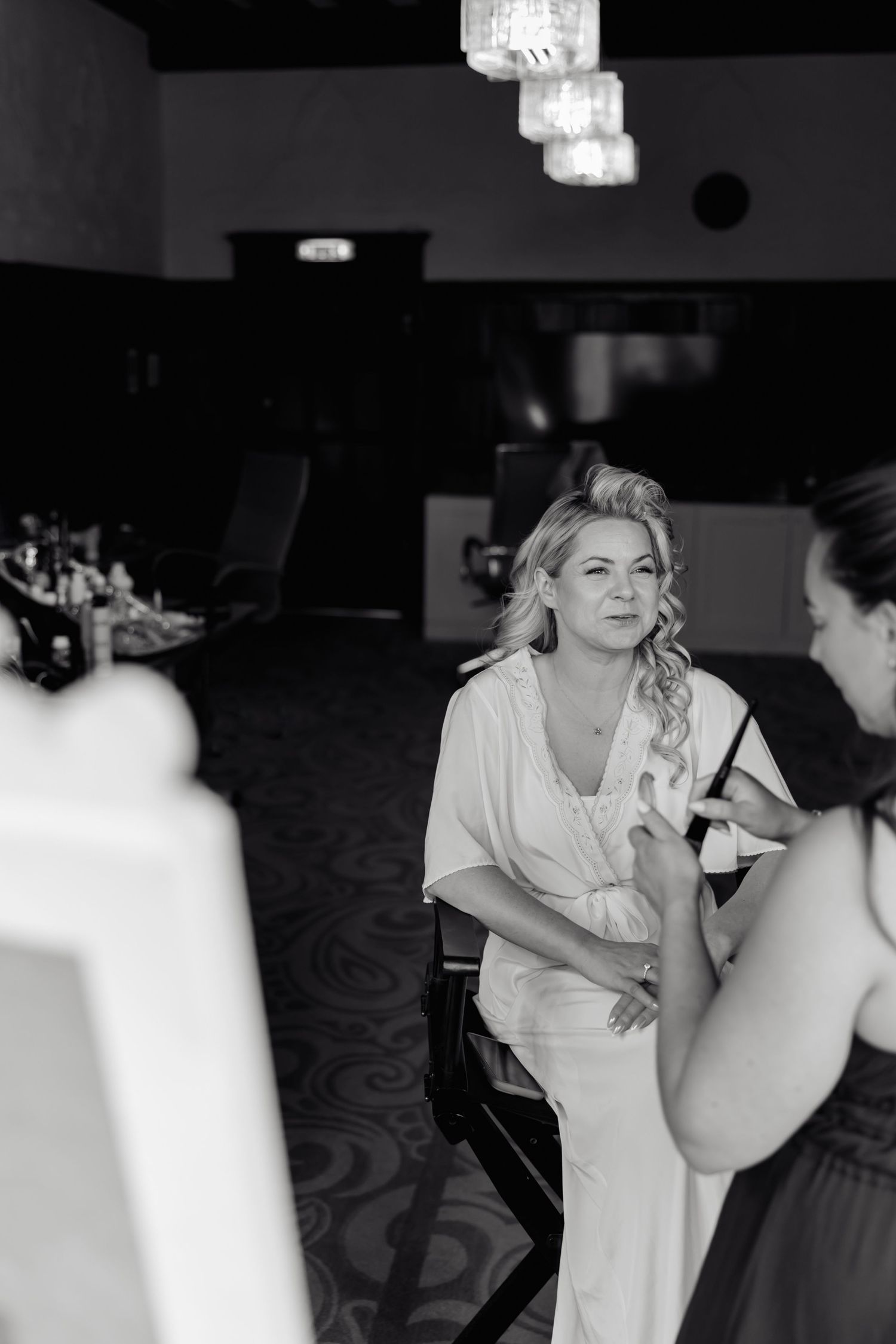 Black and white photo of wedding preparation with makeup being applied.