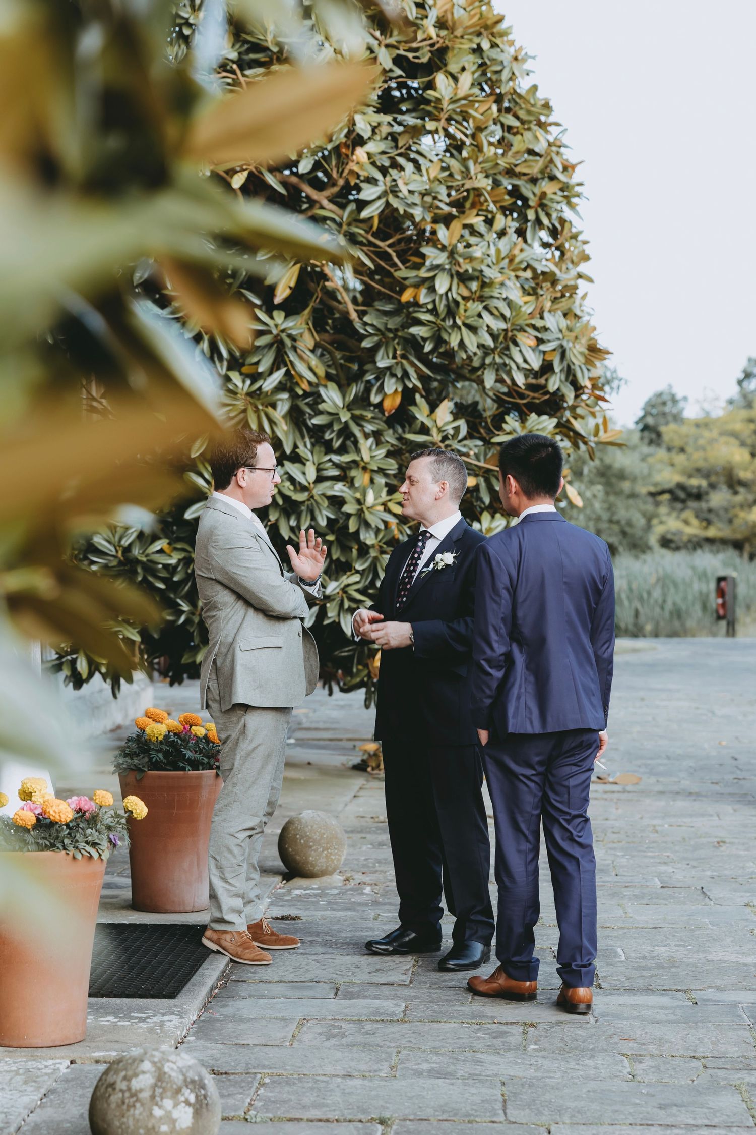 Small group gathering on a stone patio with potted plants and flowers.