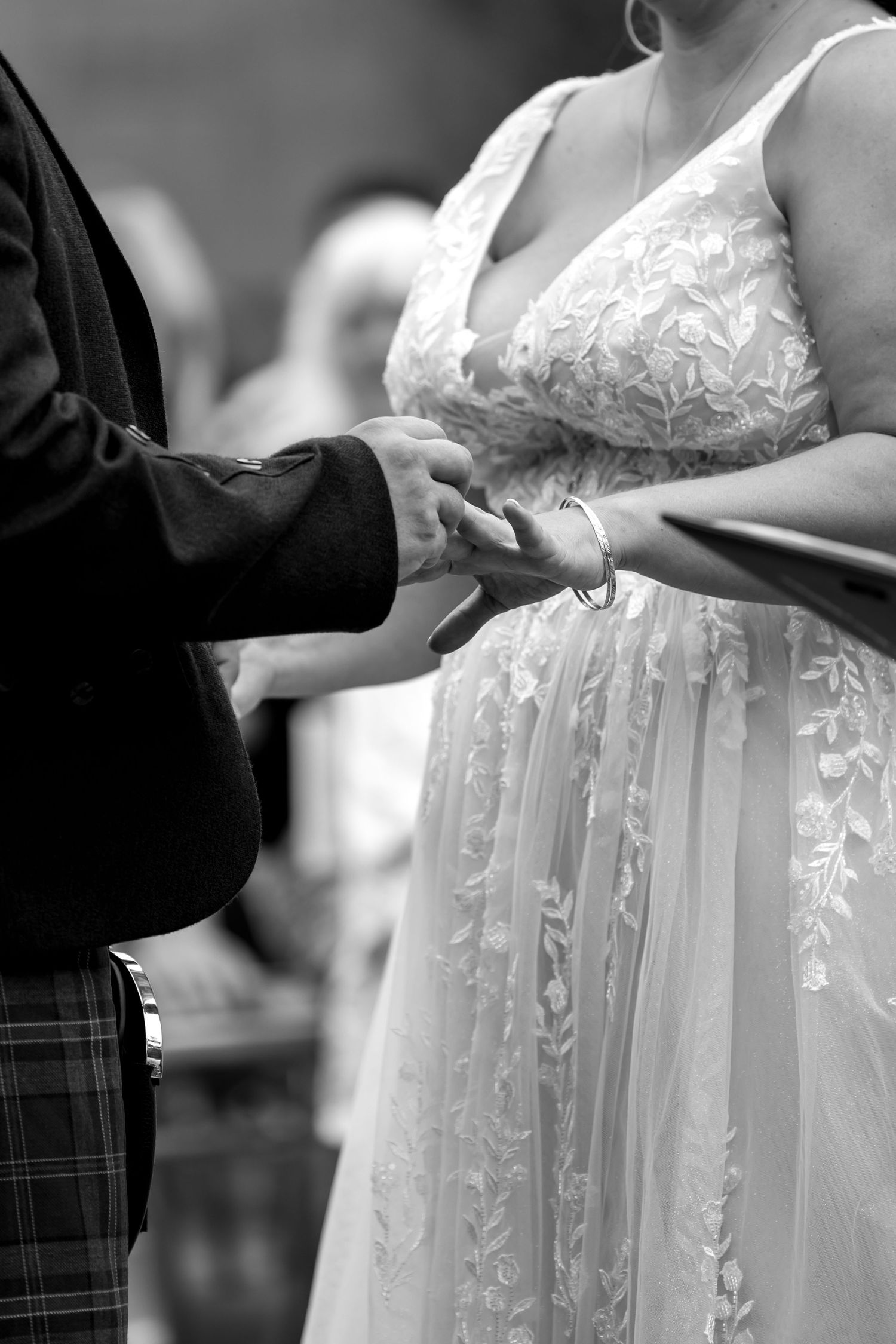 Black and white detail shots of bride's lace dress during wedding ceremony.
