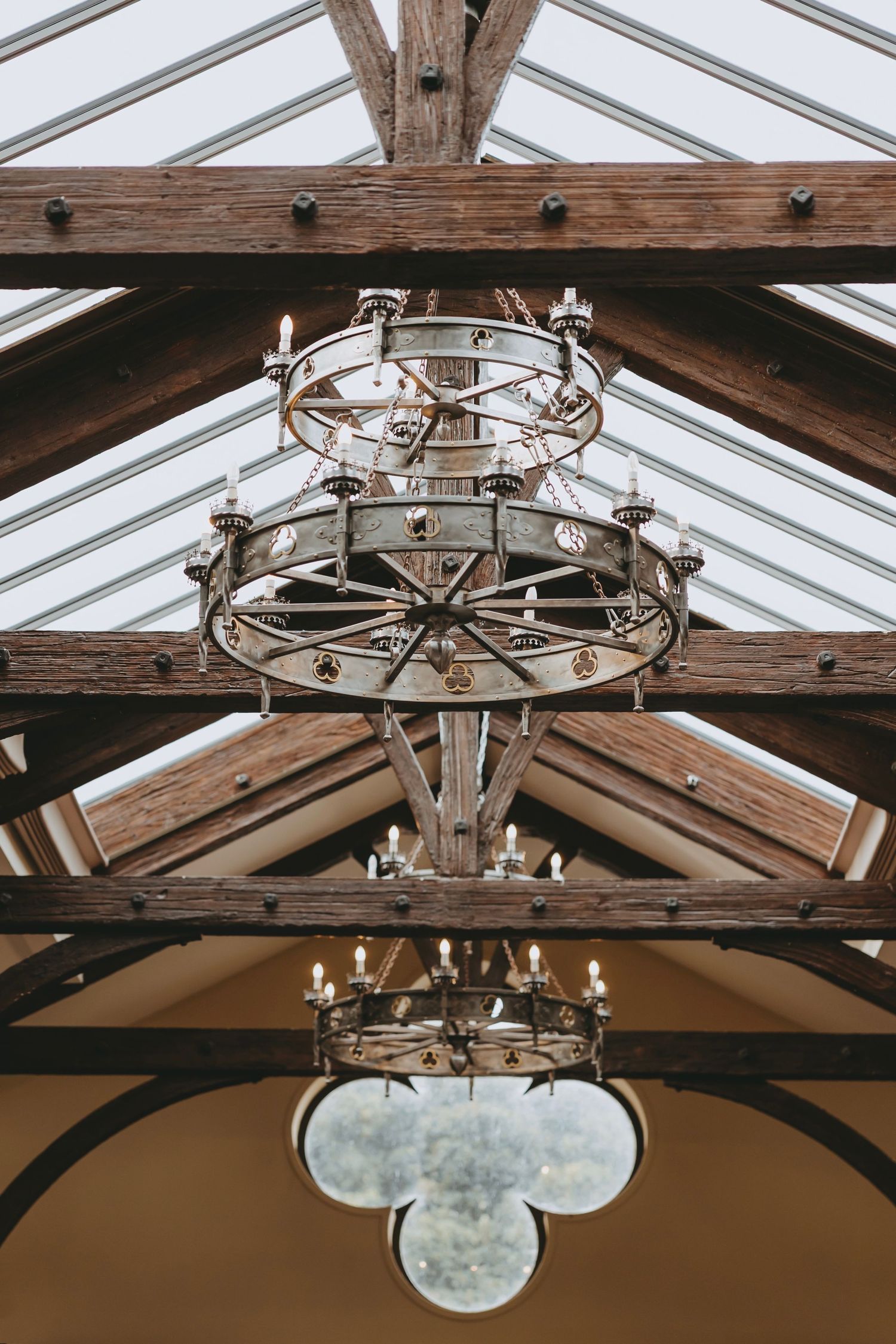 Rustic wooden beams and elegant chandeliers create ambiance in a wedding venue ceiling.