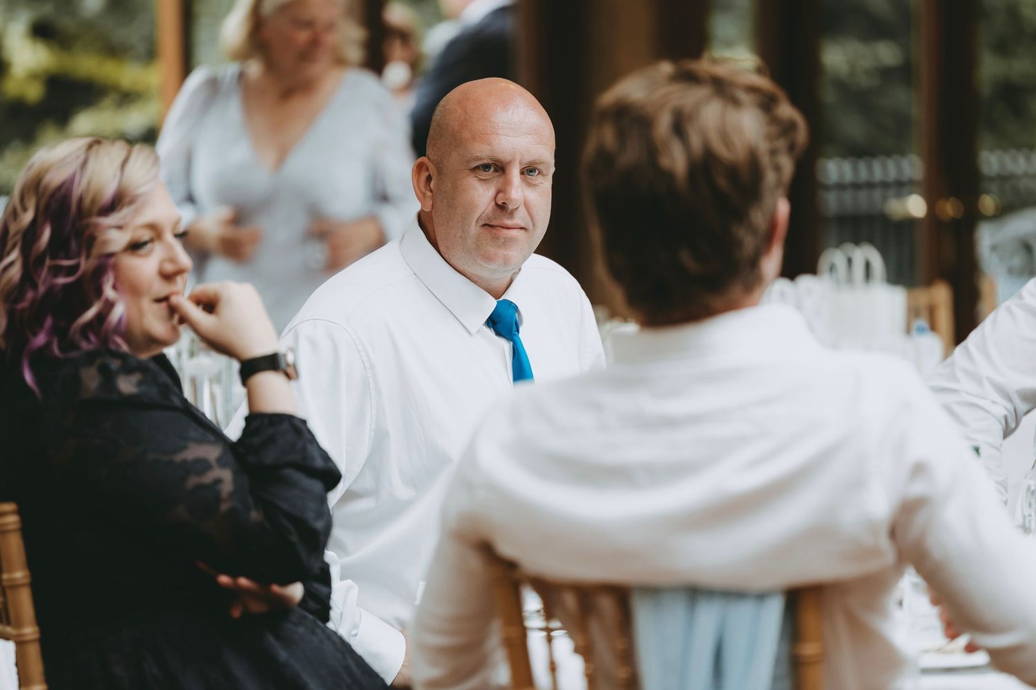 Guests engage in conversation at a formal event with elegant table settings.