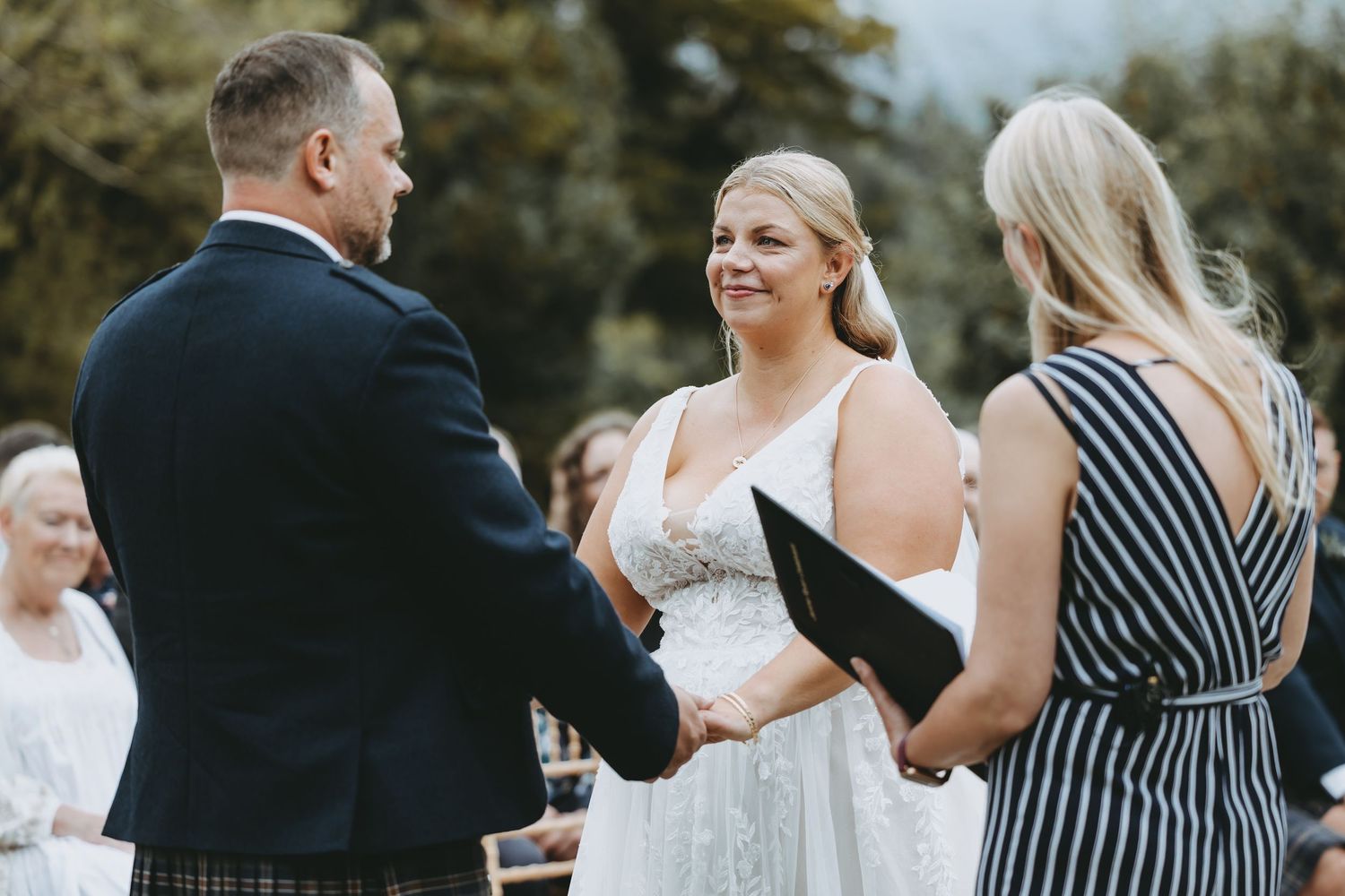 Wedding guests in formal attire participating in outdoor ceremony activities.