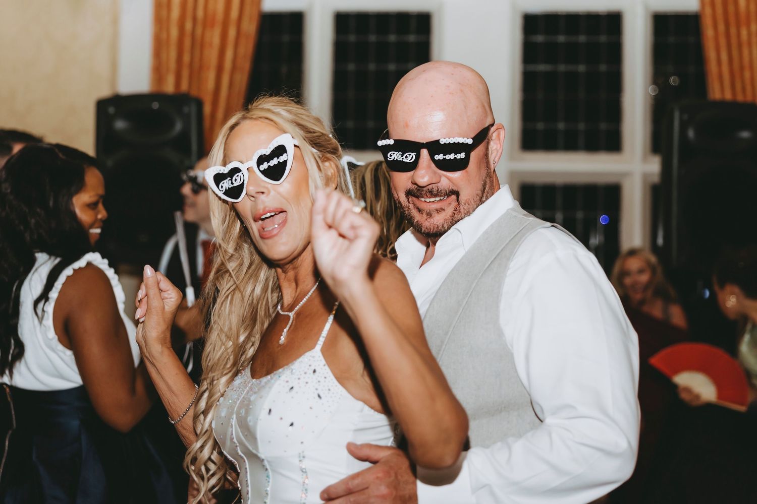 Bride and groom wearing fun novelty sunglasses dancing together at their wedding reception party.