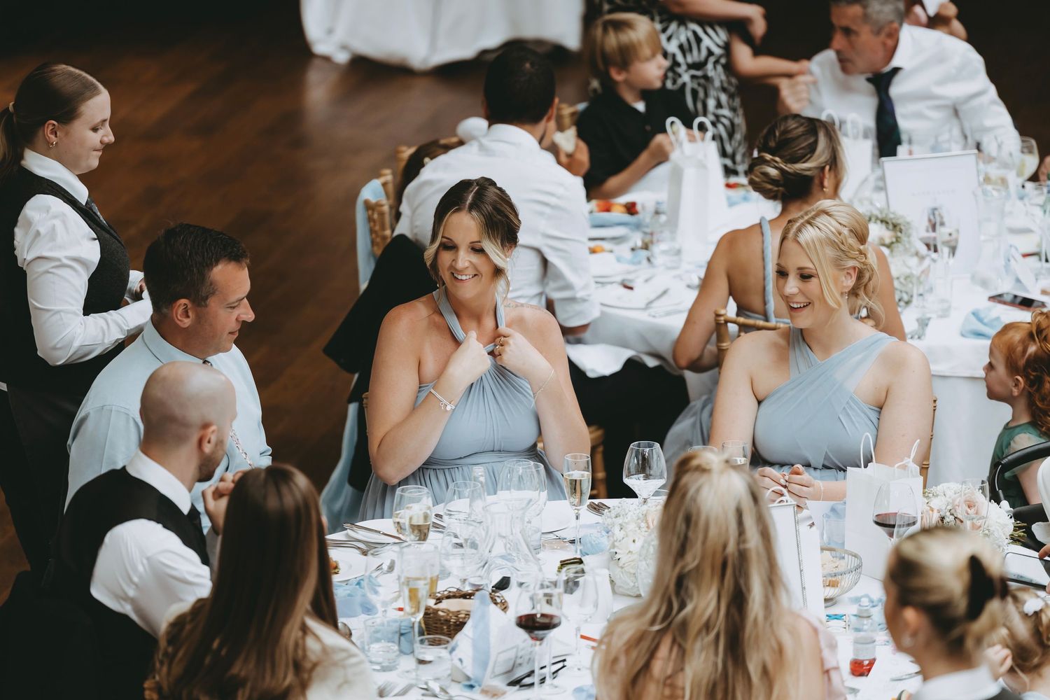 Wedding reception guests enjoying dinner and conversation at elegantly set tables.