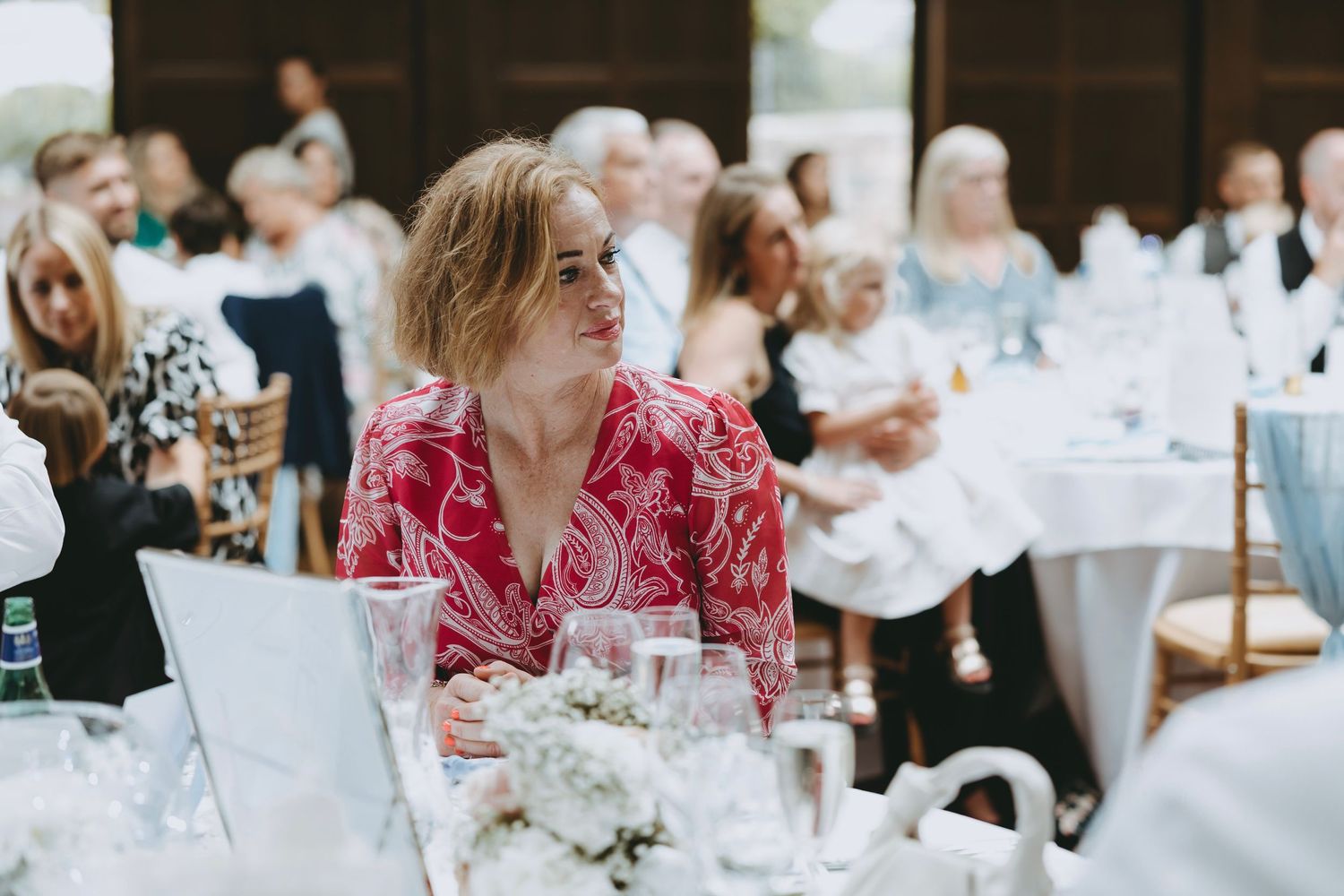 Wedding reception guests seated at round tables decorated with white linens.