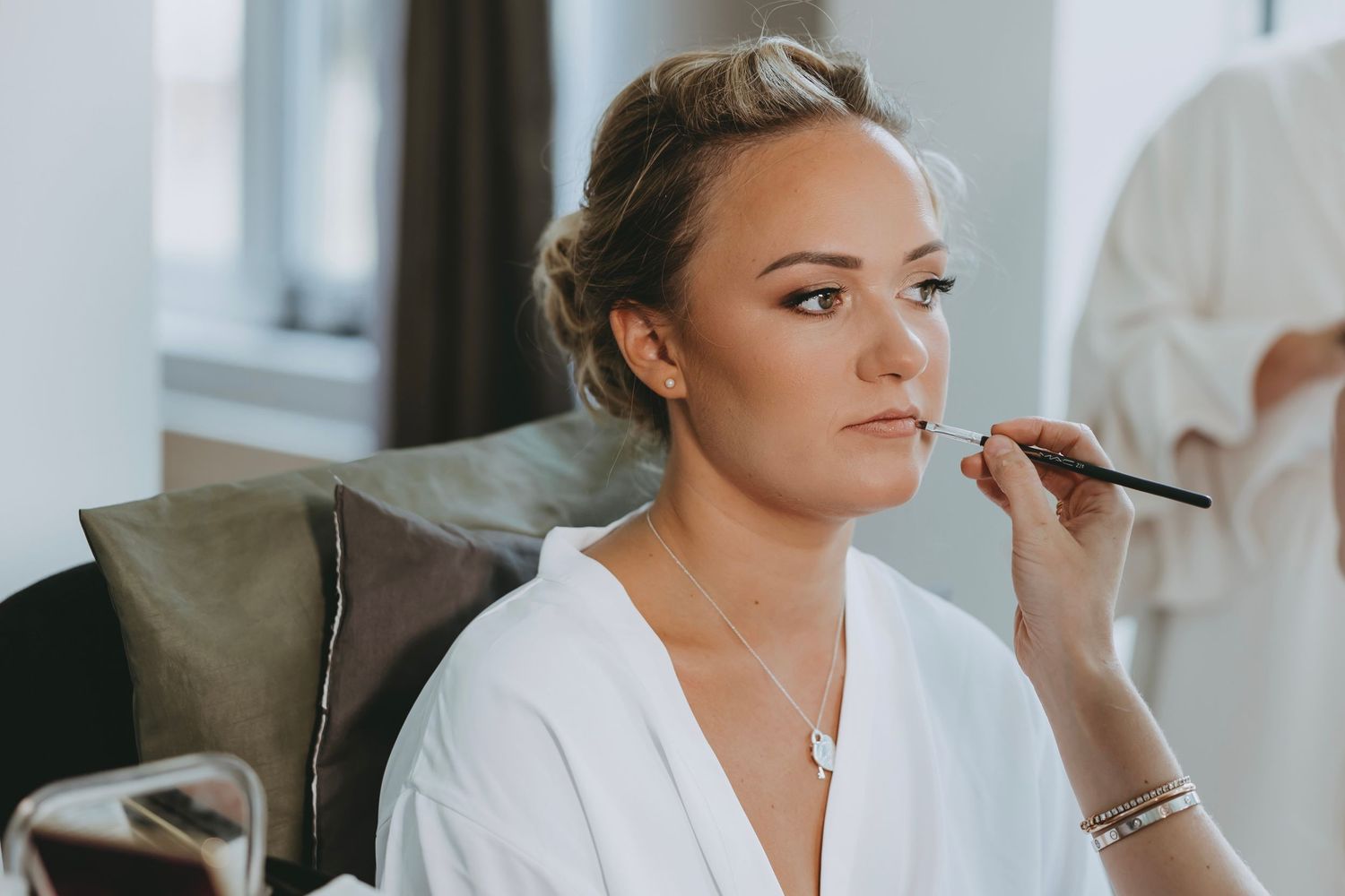 Wedding morning preparations in a bright sunlit room with white decor.