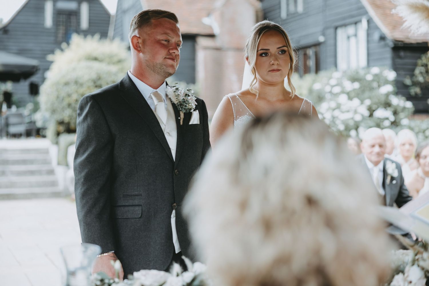 Couple stands at altar during outdoor wedding ceremony with white flowers.