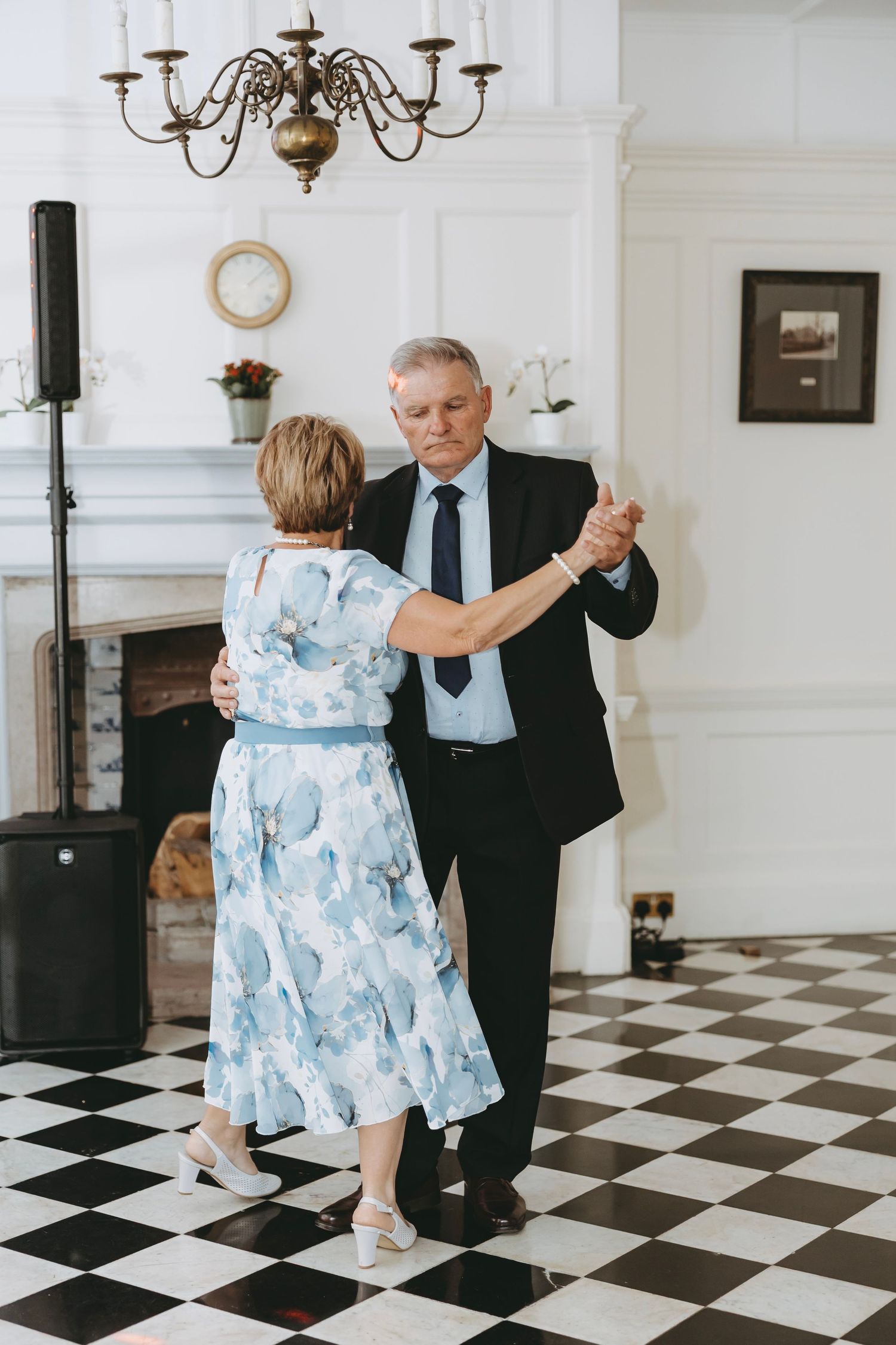 Couple performing dance moves together on black and white checkered floor.