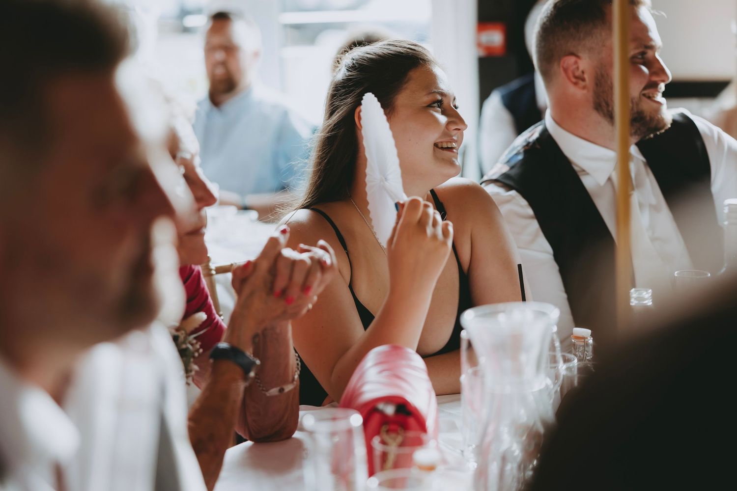 Wedding reception guests laugh and smile during celebratory speeches.