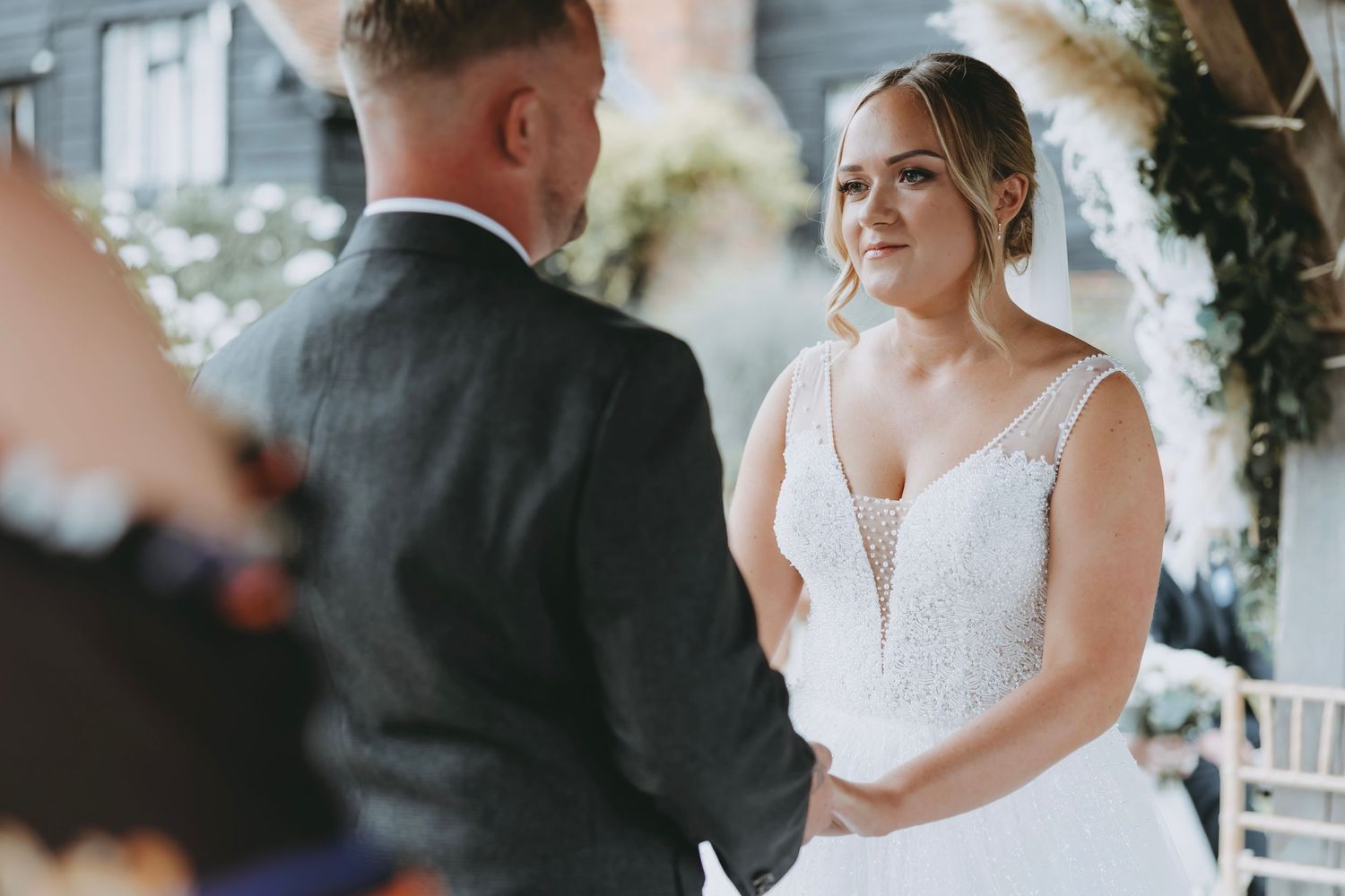 Couple shares emotional moment during wedding ceremony under floral arch.