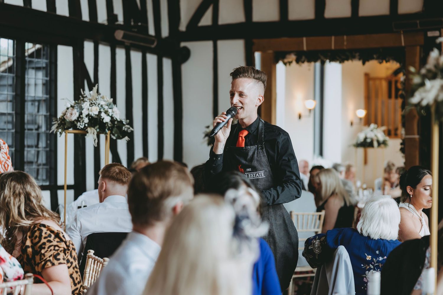 Wedding guests gathered in a traditional Tudor-style venue for the reception.