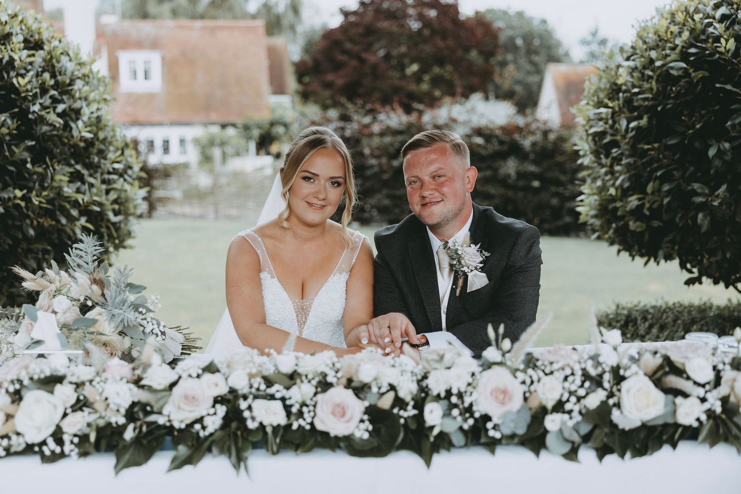 A tender wedding moment shared between a couple in a garden with elegant floral arrangements.