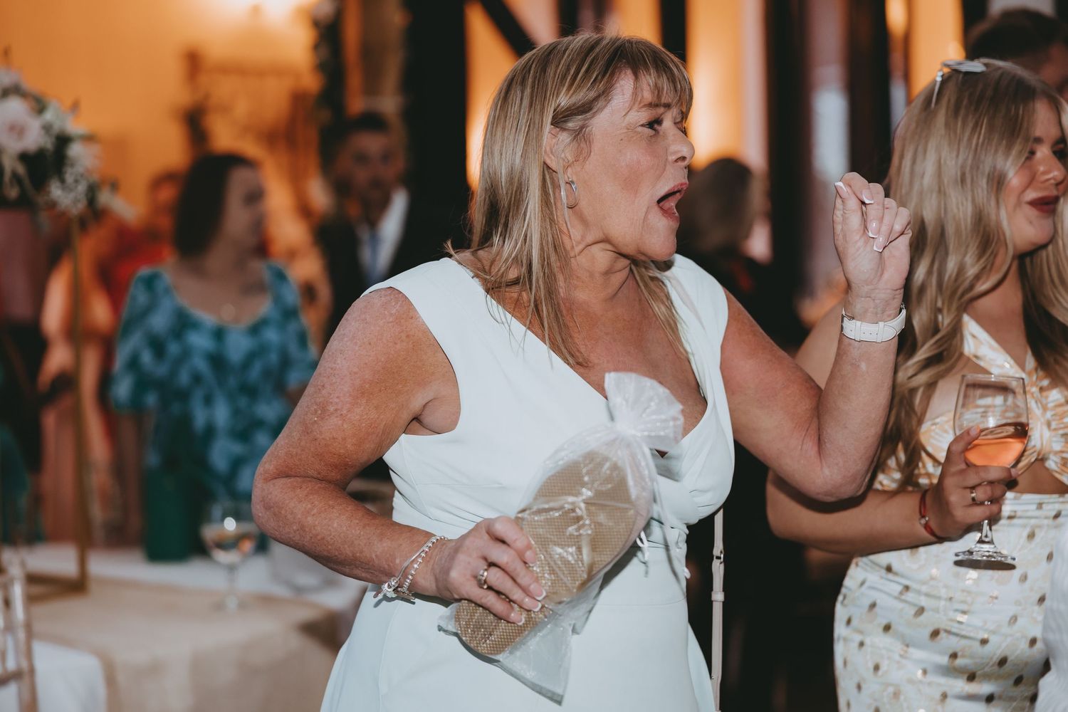 Wedding celebration with guests dancing and socializing in warm ambient lighting.