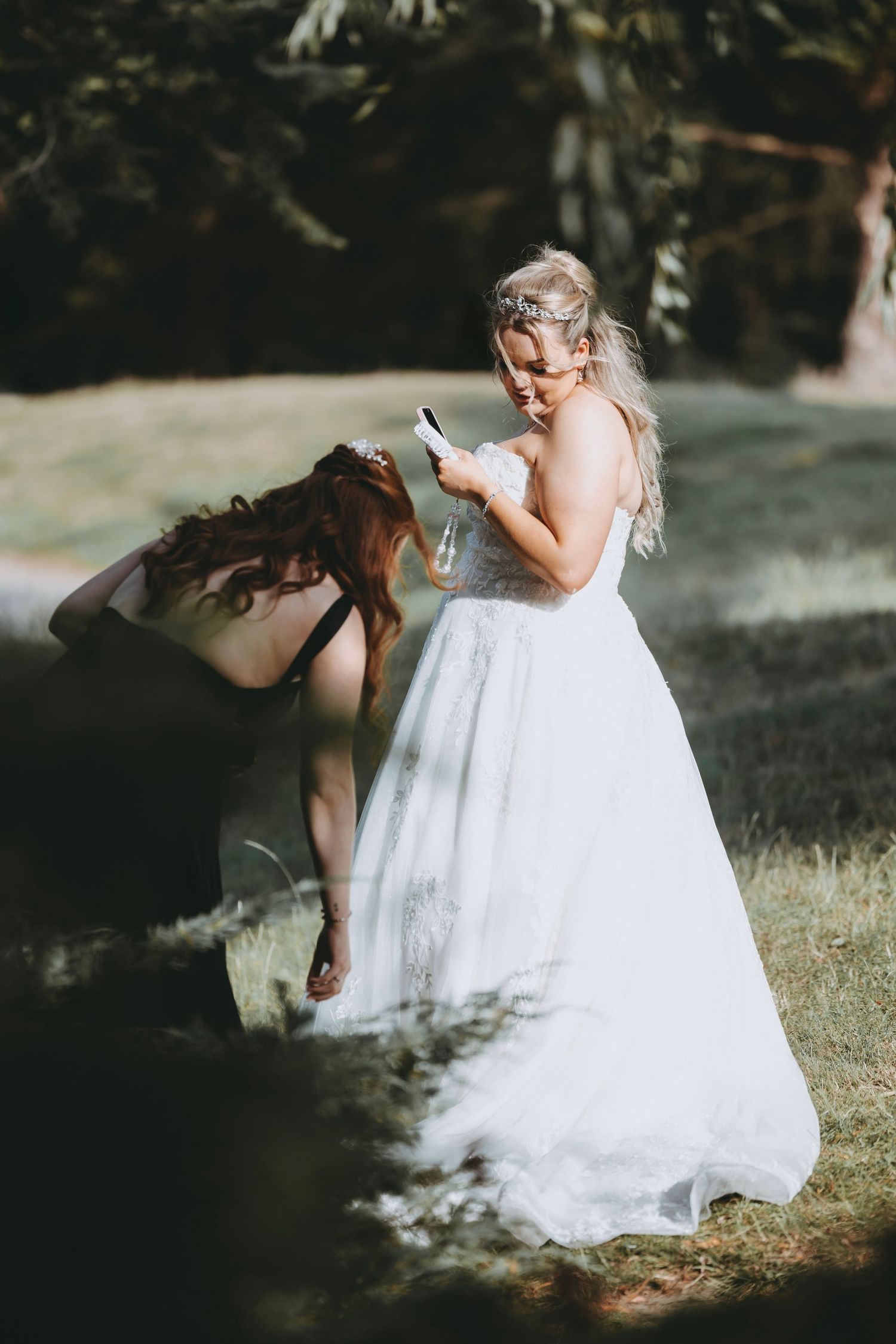 Young flower girl in white dress playing outdoors during wedding celebration.