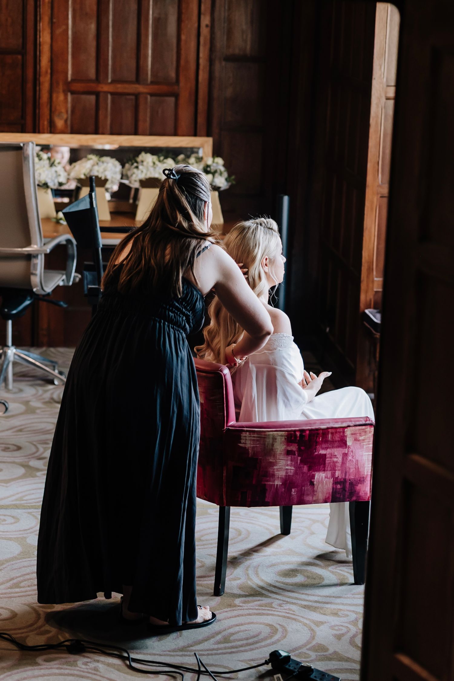 Bridesmaids in navy dresses helping with wedding preparations in a classic interior.