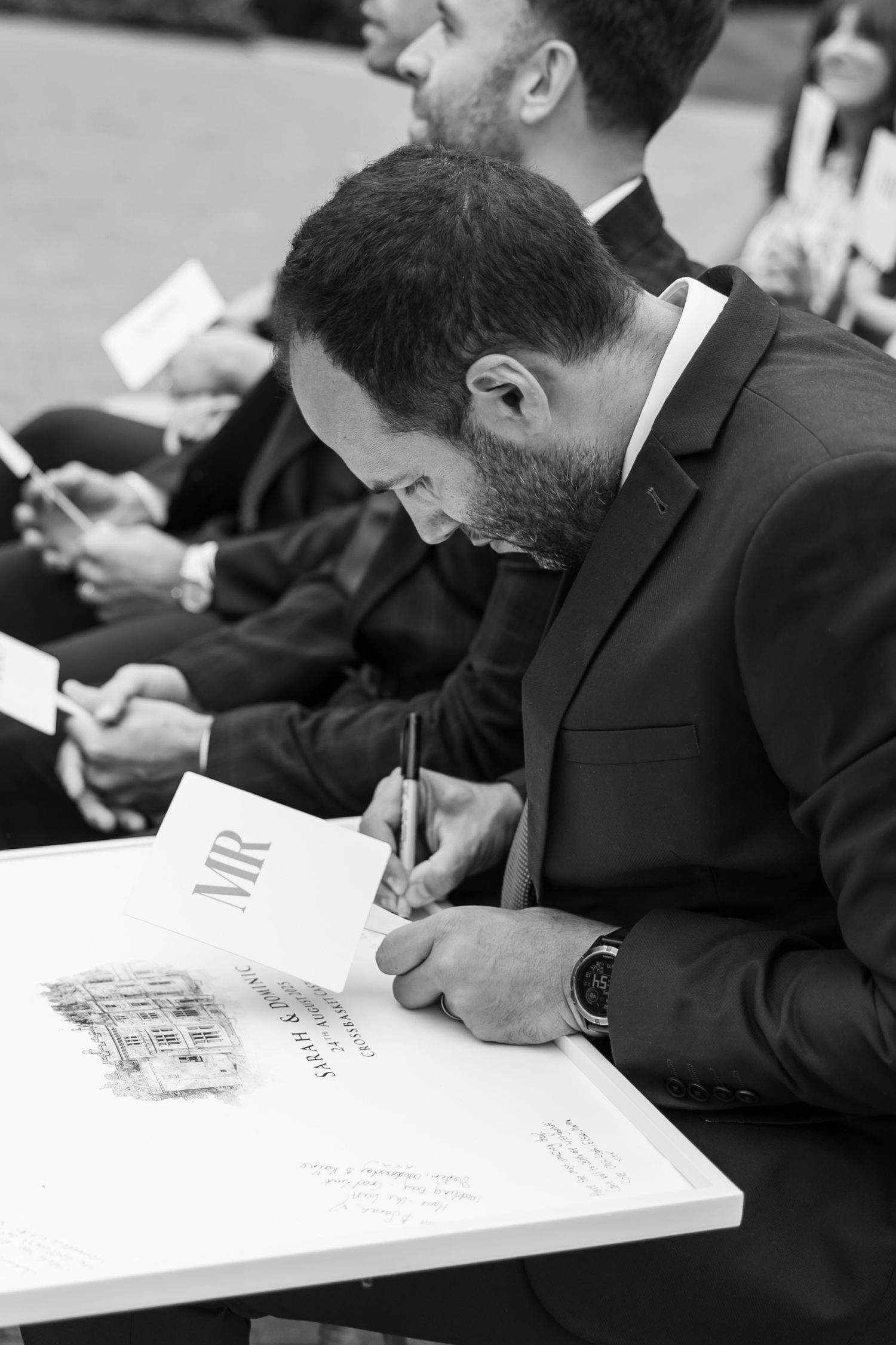 People in formal attire signing documents at a table.