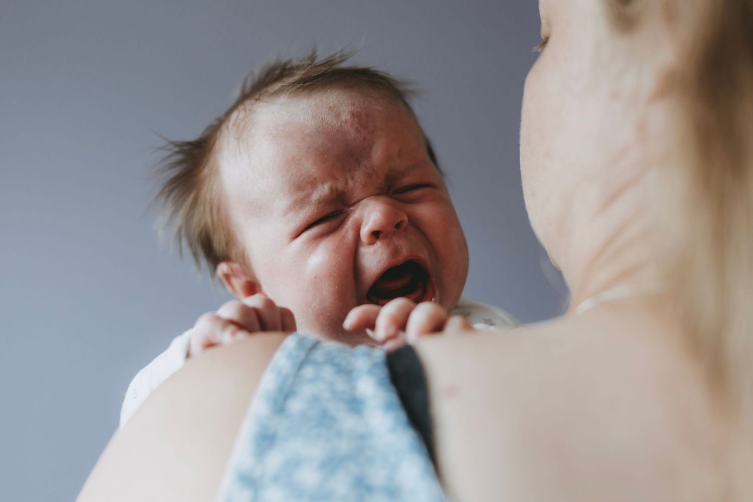 A crying baby in a polka dot onesie showing different emotional expressions.