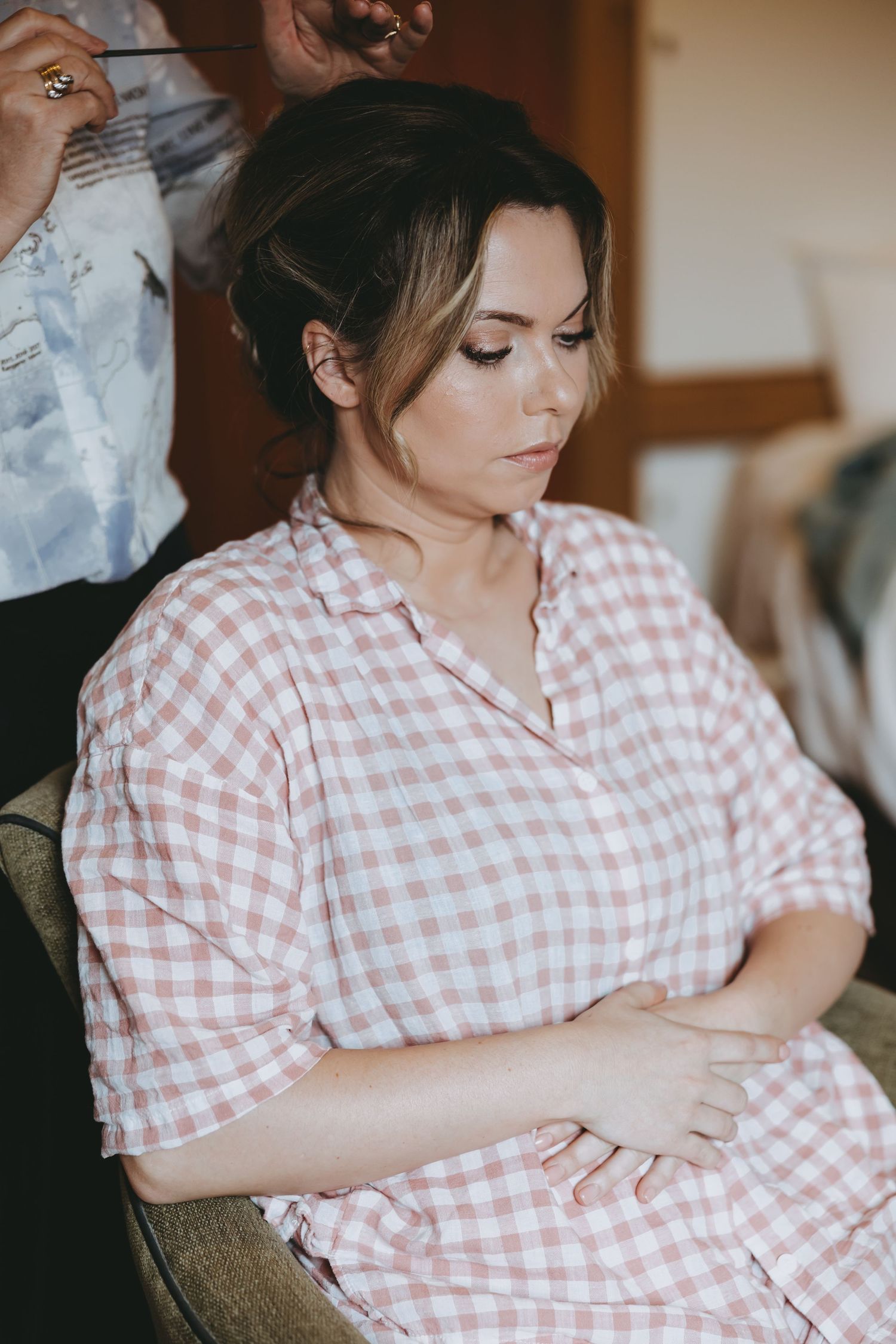 Person wearing pink gingham dress seated in soft natural light.