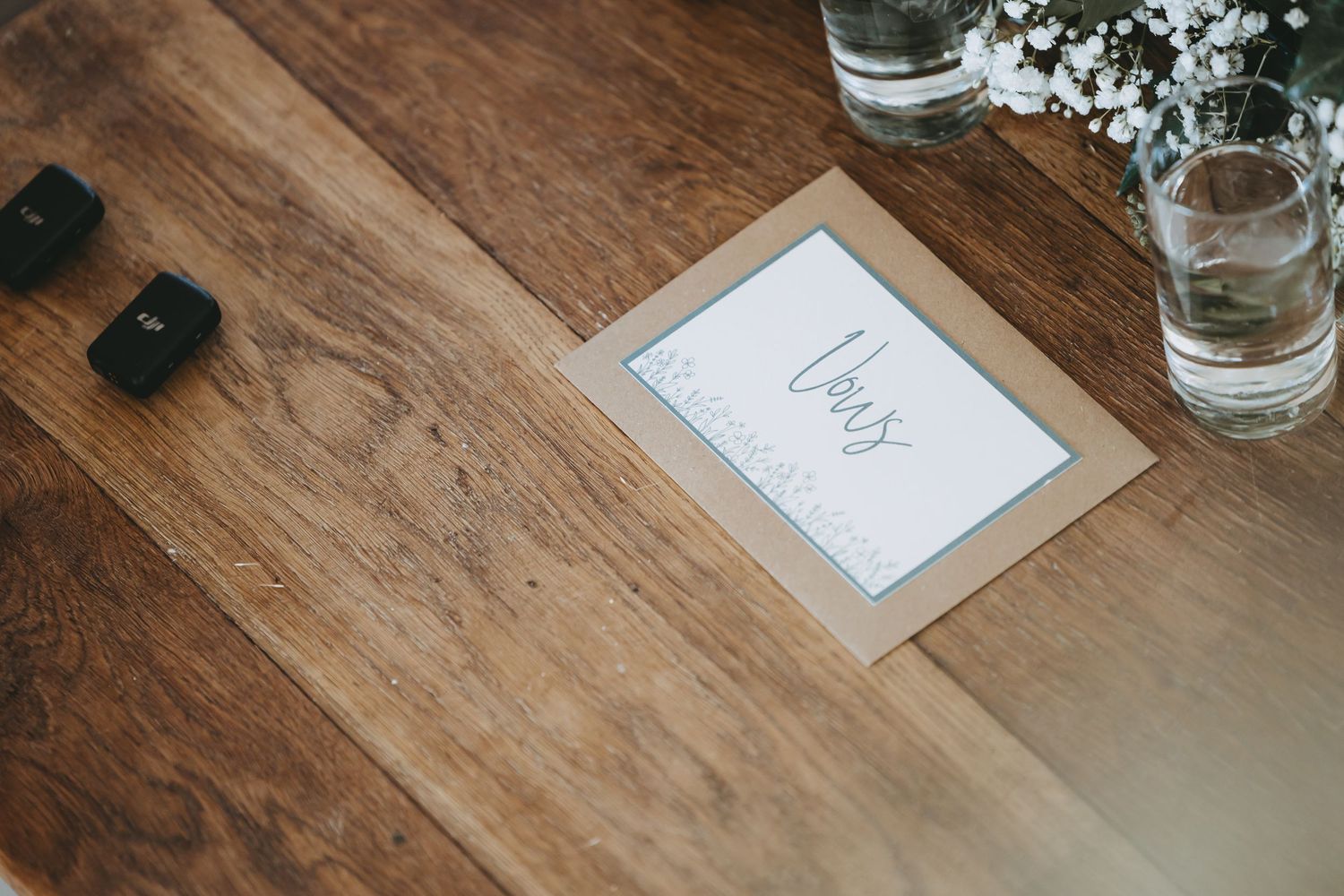 Wedding place settings on a wooden table with delicate white flowers and glassware.