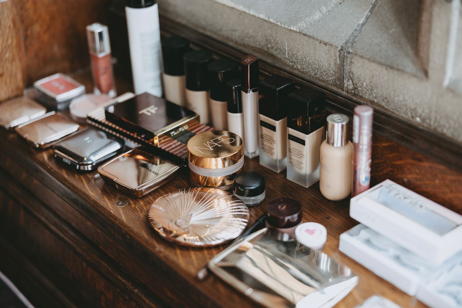 Beauty products and cosmetics displayed on rustic wooden vanity surface.