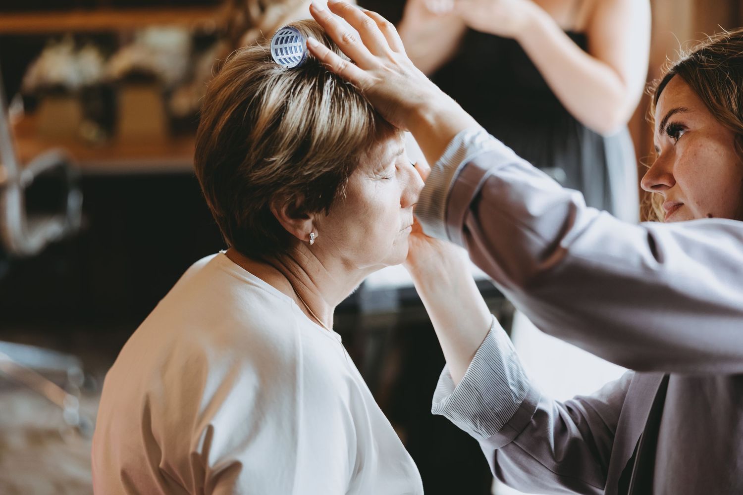 Bride getting her hair styled in an elegant room with natural lighting.