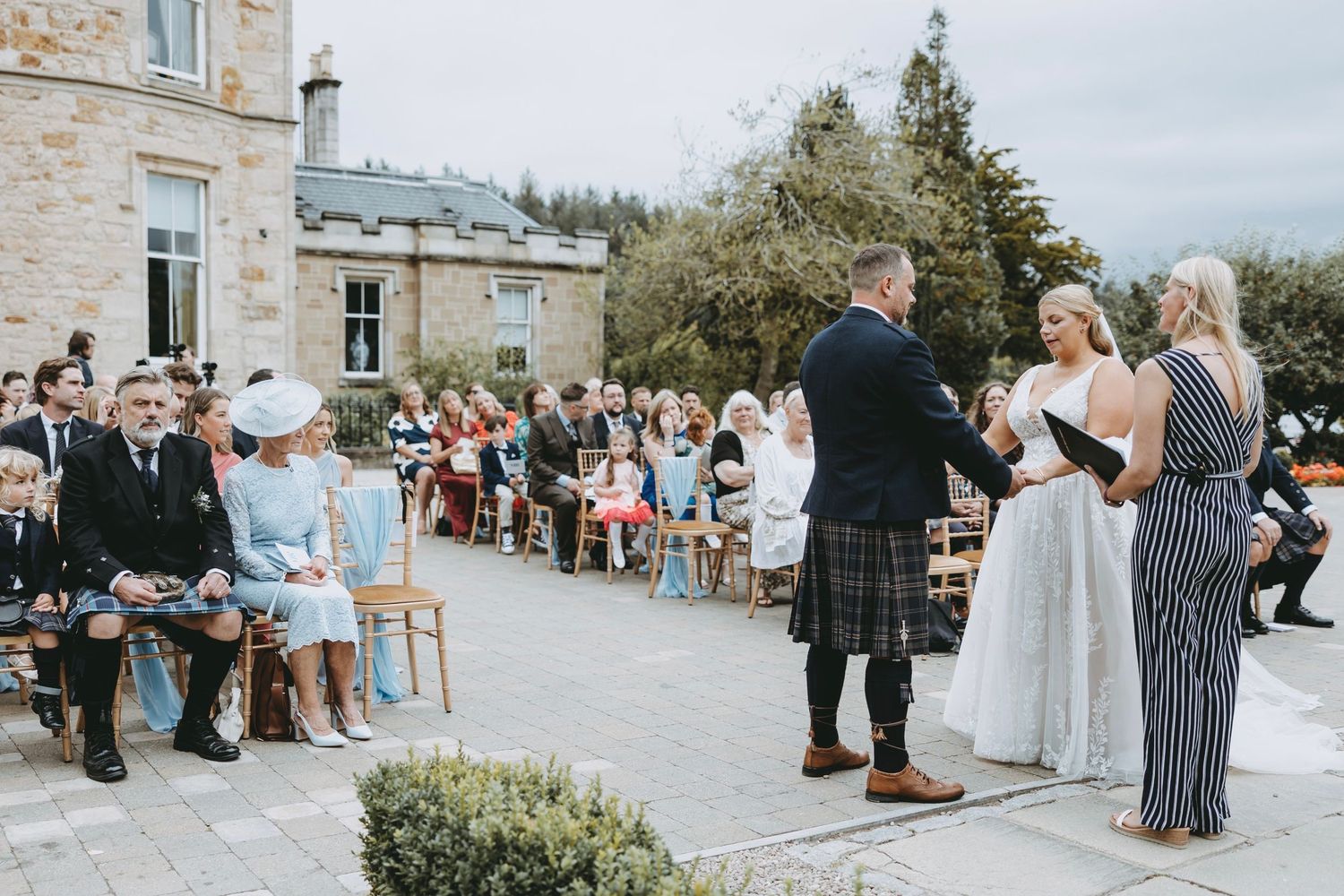 Stone venue exterior with wedding guests gathered for an outdoor celebration.