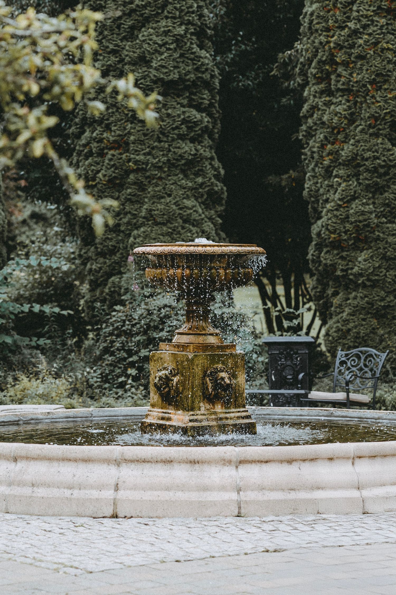 Ornate golden fountain in a manicured garden setting.