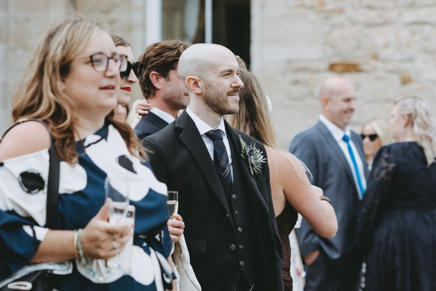 Wedding guests socialize during outdoor reception at stone venue.