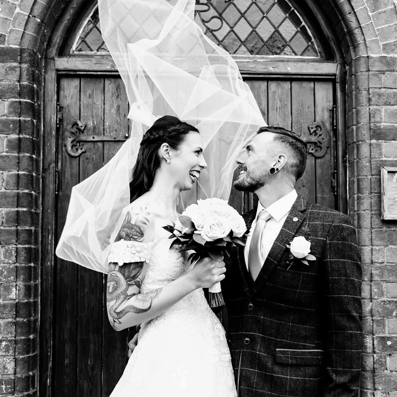 Black and white wedding photo collage showing happy couple laughing and embracing in front of brick archways.
