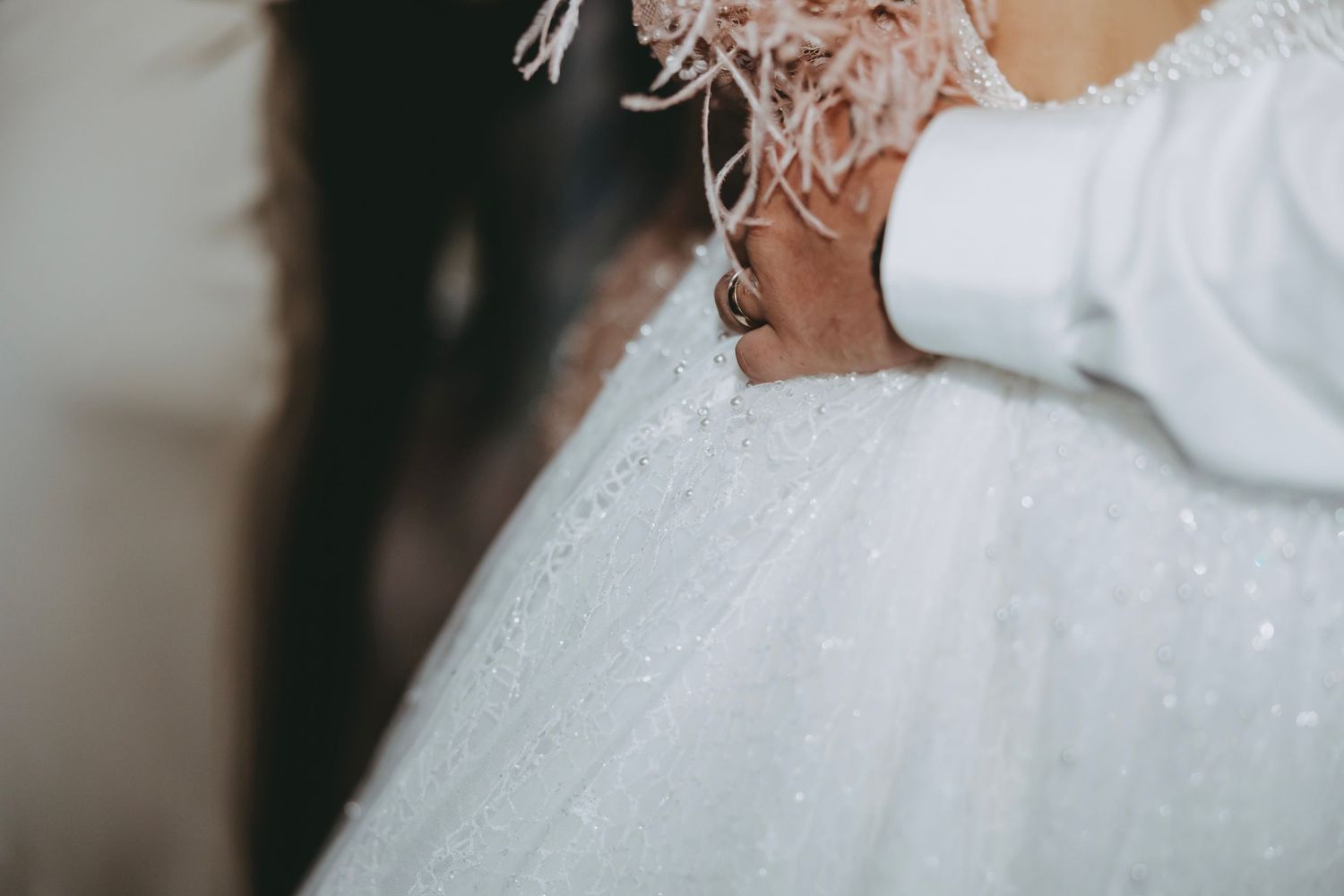 Close-up detail of feather-trimmed white wedding dress.