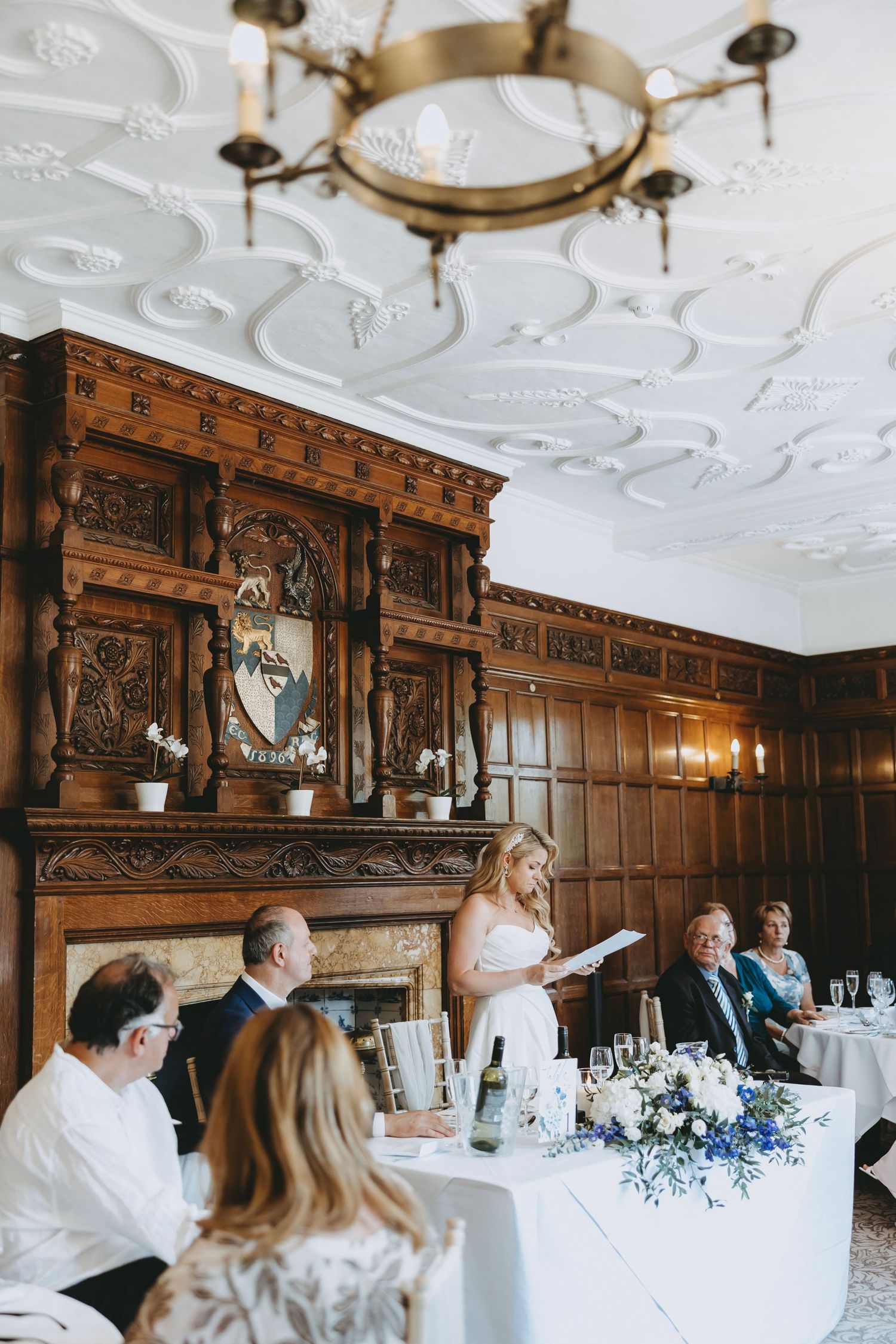Elegant wedding reception in a historic room with ornate wood paneling and decorative ceiling.