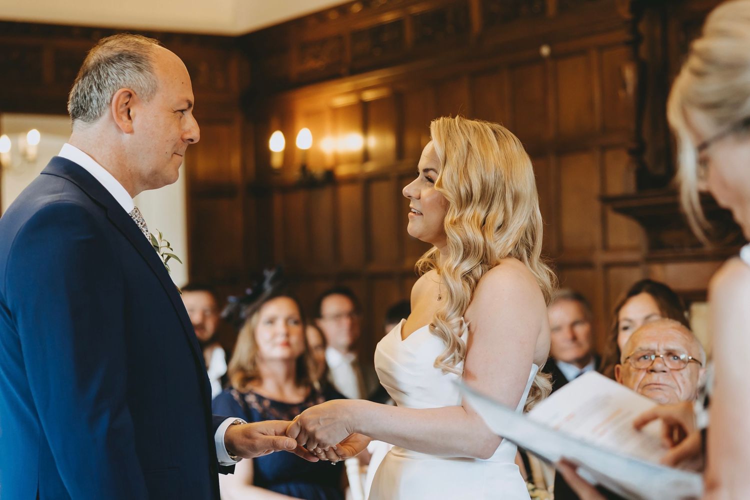 Intimate wedding ceremony moment in a grand room with wood paneling.