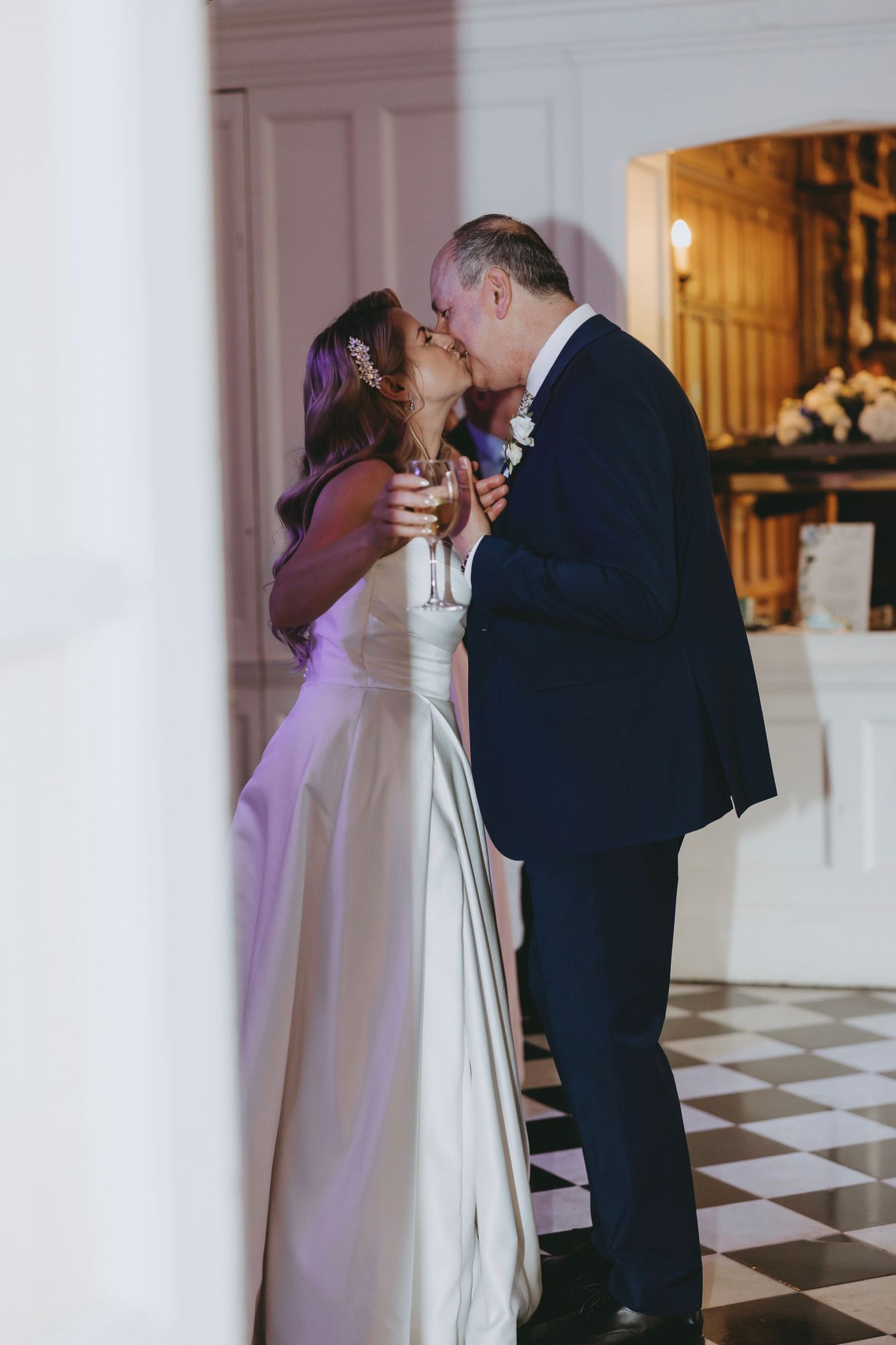 Romantic dance scene at a wedding reception with couples swaying on a checkered dance floor.