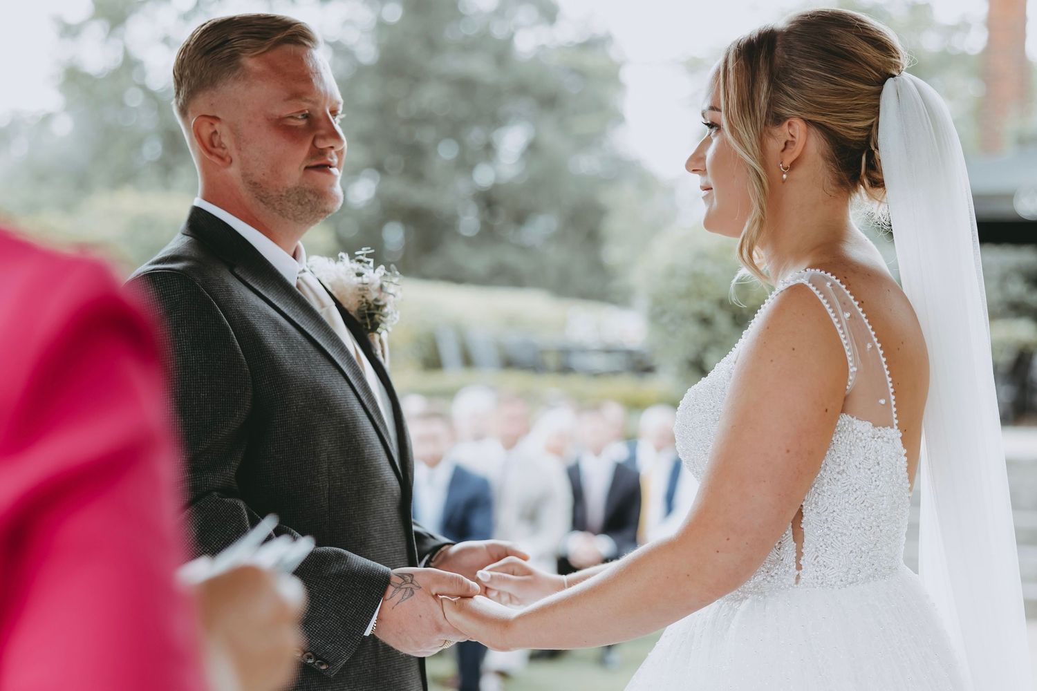 Couple holding hands during outdoor wedding ceremony.