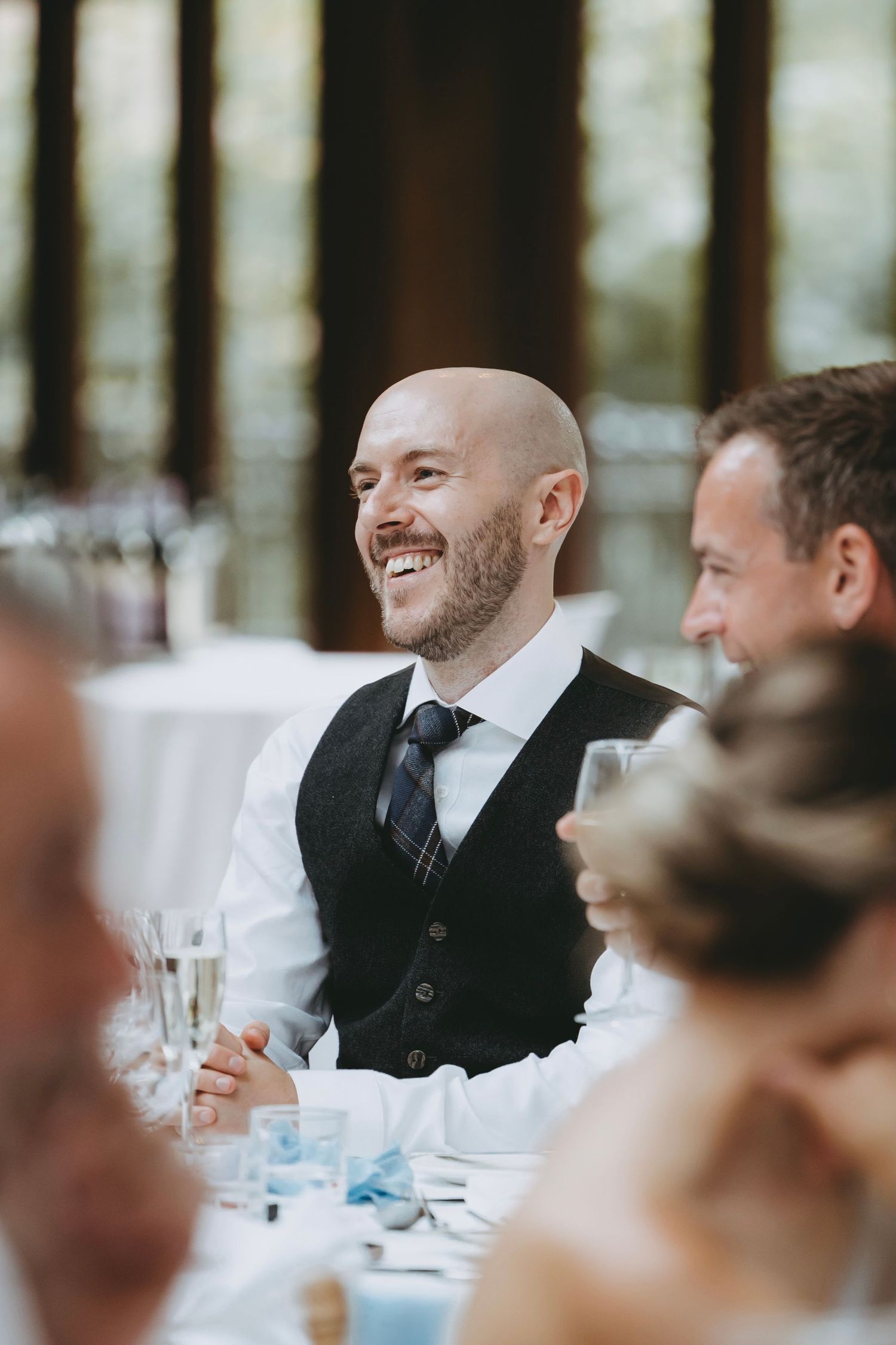 Reception table setting with guests enjoying conversation during wedding celebration.