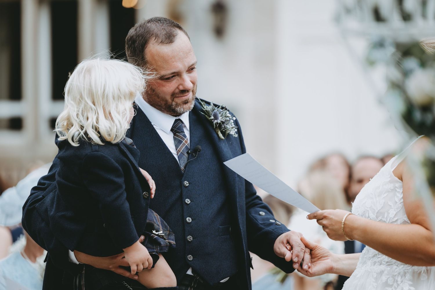 Intimate wedding ceremony moment captured under decorative white floral arches.