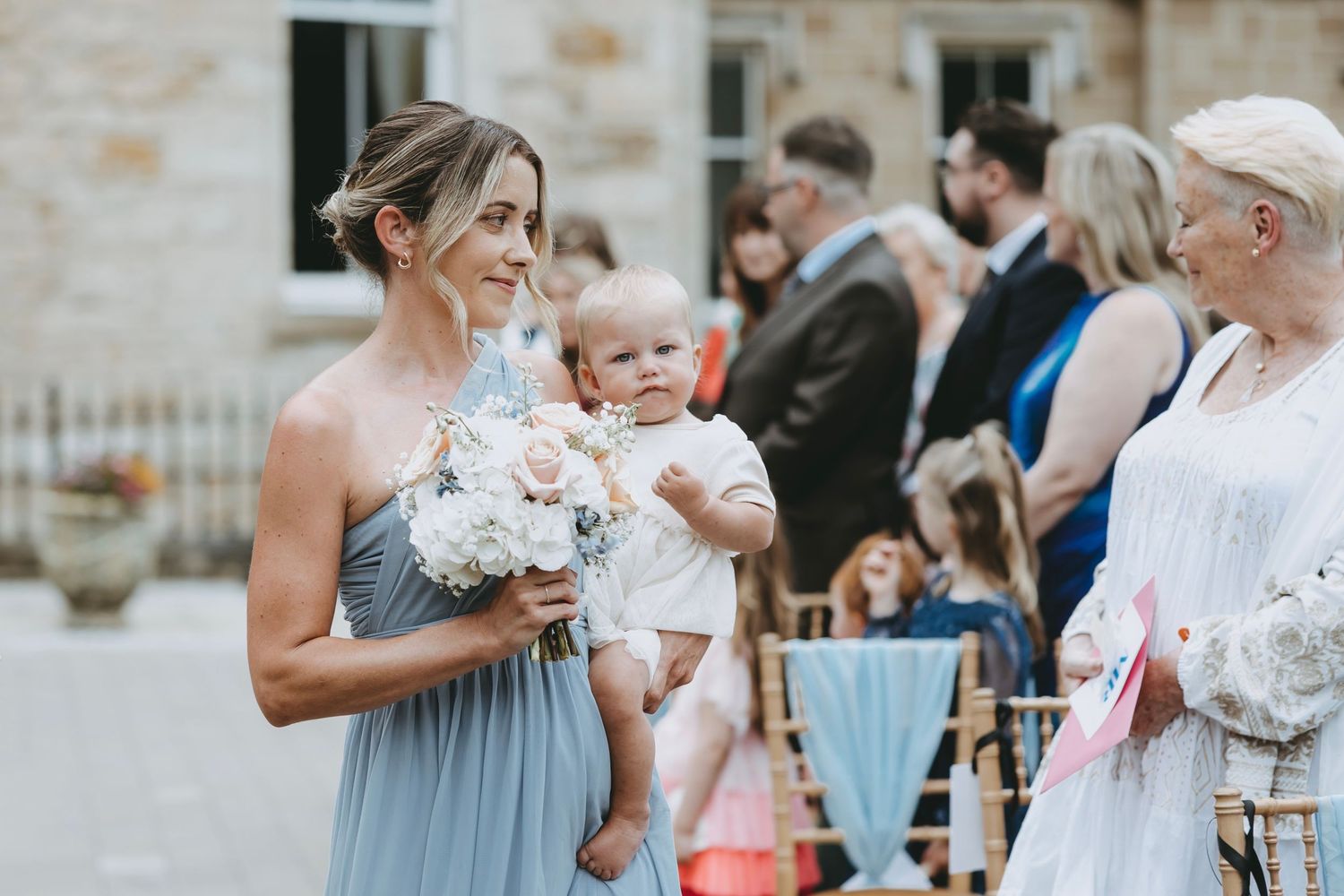 Wedding guests in formal attire gathered at outdoor stone venue for celebration.
