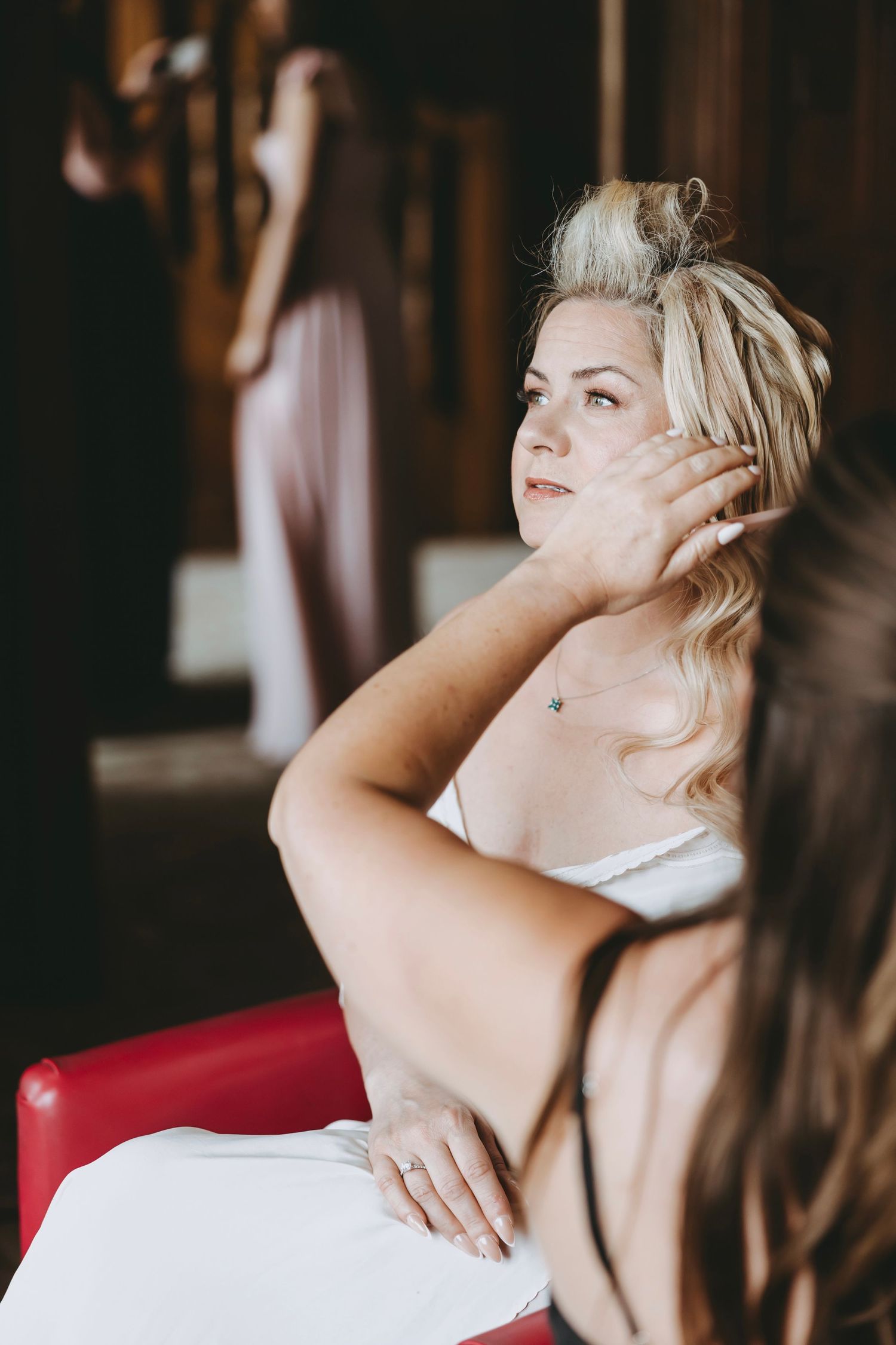 Artistic black and white portrait of wedding preparations on red velvet chair.